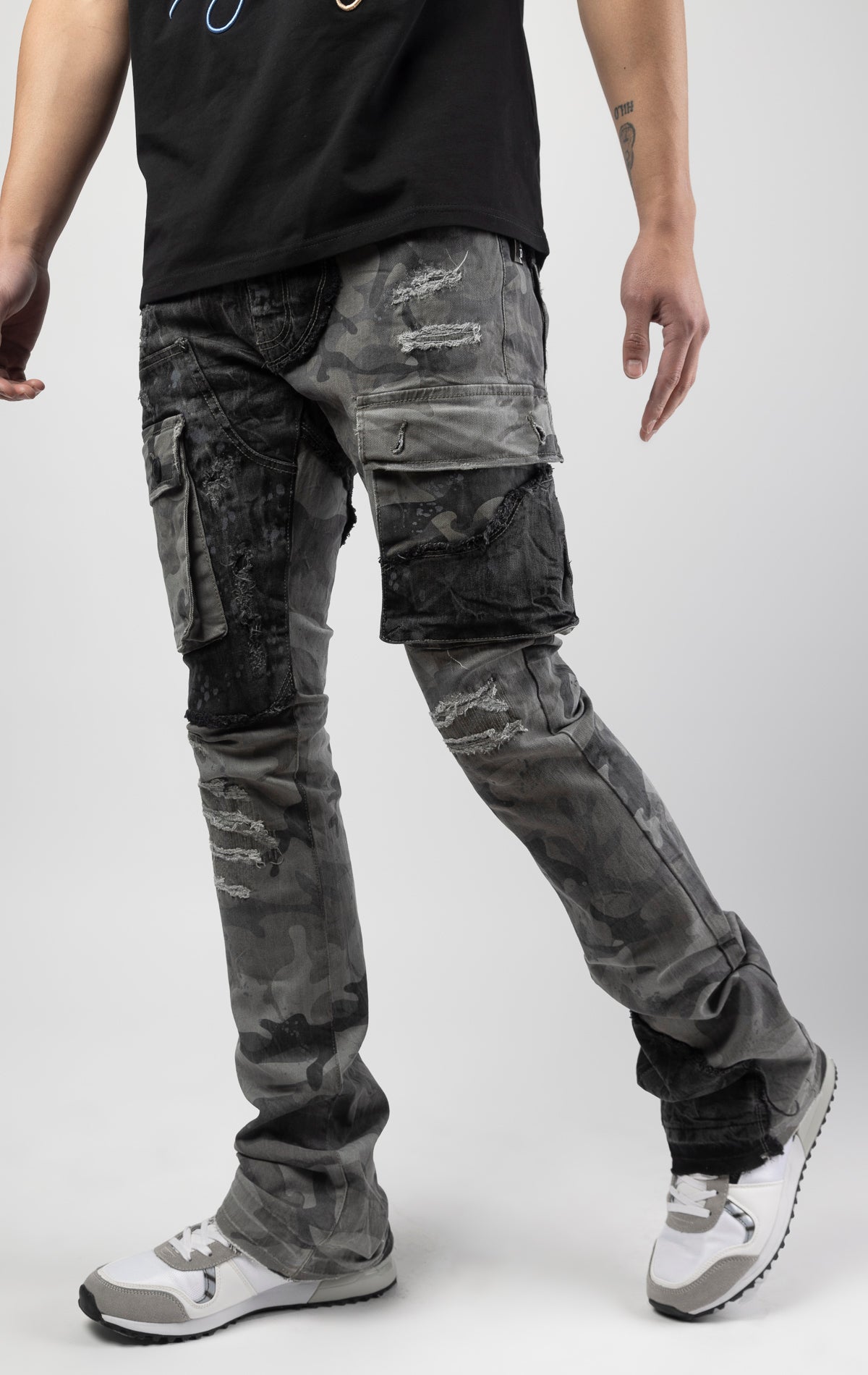 Black camo Extended length flare pant with a regular rise for maximum stacks. Skinny fit with hand-smearing and speckled paint splatter throughout. Rip and repair detailing, accompanied by cut & sewn woodland camouflage twill patches. Stitching repairs an
