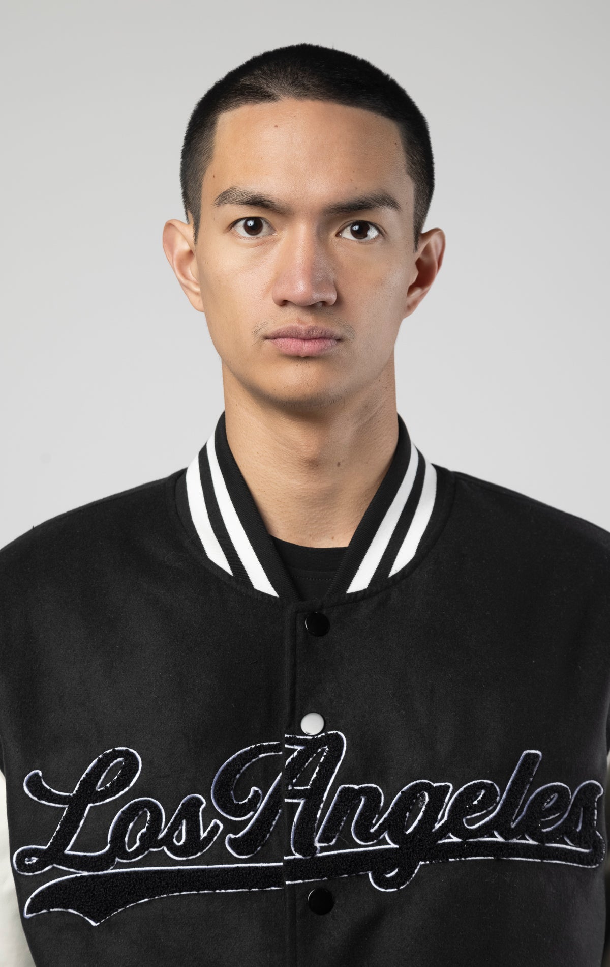 Black and white Los Angeles varsity jacket featuring a sleek button closure, ribbed cuffs, and a satin lining for added comfort.