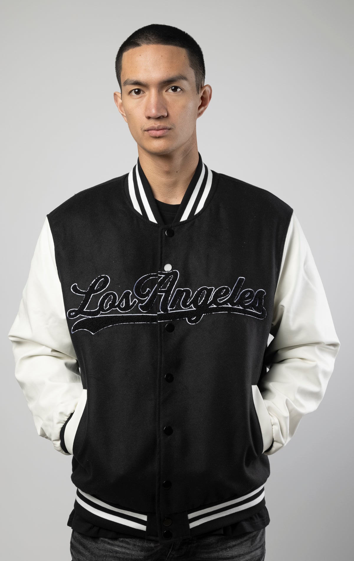 Black and white Los Angeles varsity jacket featuring a sleek button closure, ribbed cuffs, and a satin lining for added comfort.