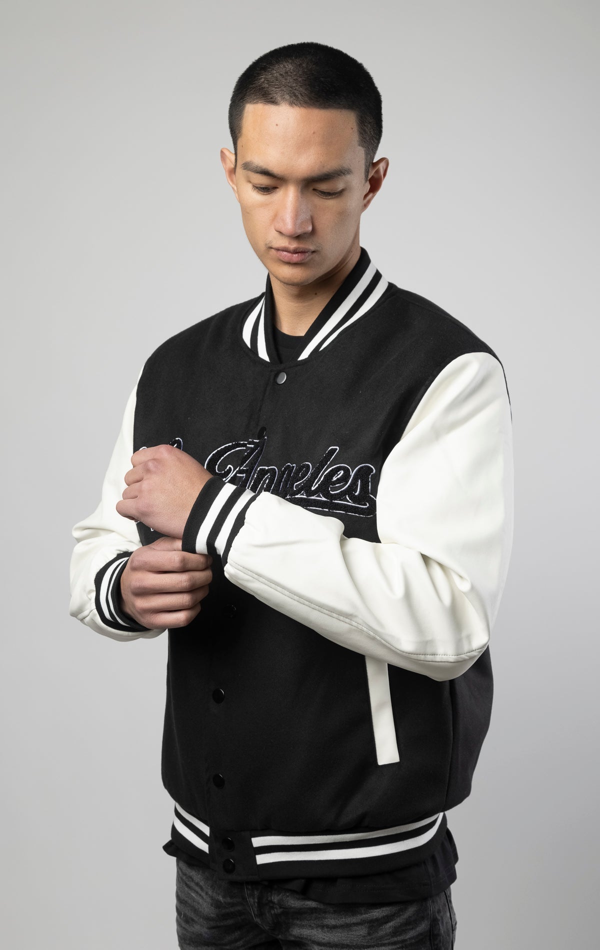Black and white Los Angeles varsity jacket featuring a sleek button closure, ribbed cuffs, and a satin lining for added comfort.