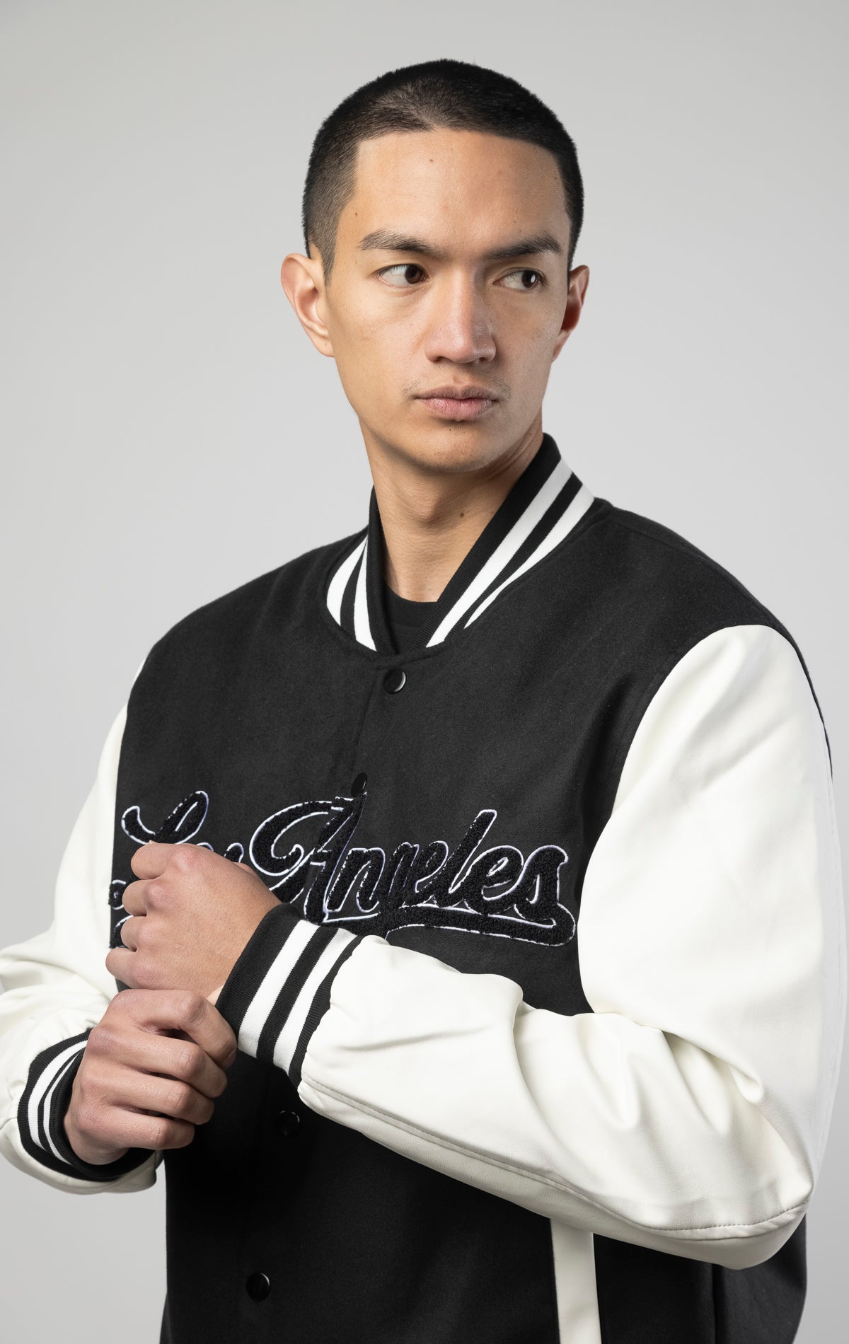 Black and white Los Angeles varsity jacket featuring a sleek button closure, ribbed cuffs, and a satin lining for added comfort.