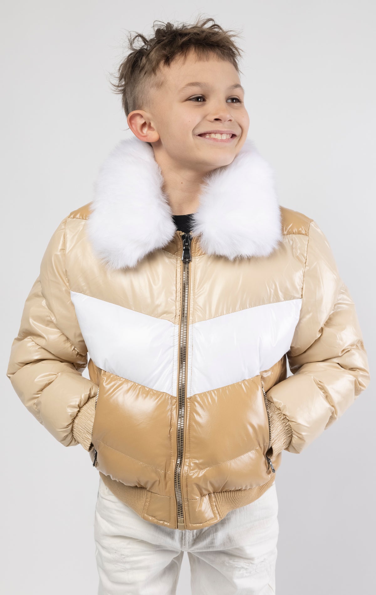 This kids' puffer jacket features a 100% nylon laqué shell, quilted padding, and 100% polyester lining. It also includes branded Jordan Craig zippers, dual side pockets with zipper closure, and a removable faux jackal fur collar.
