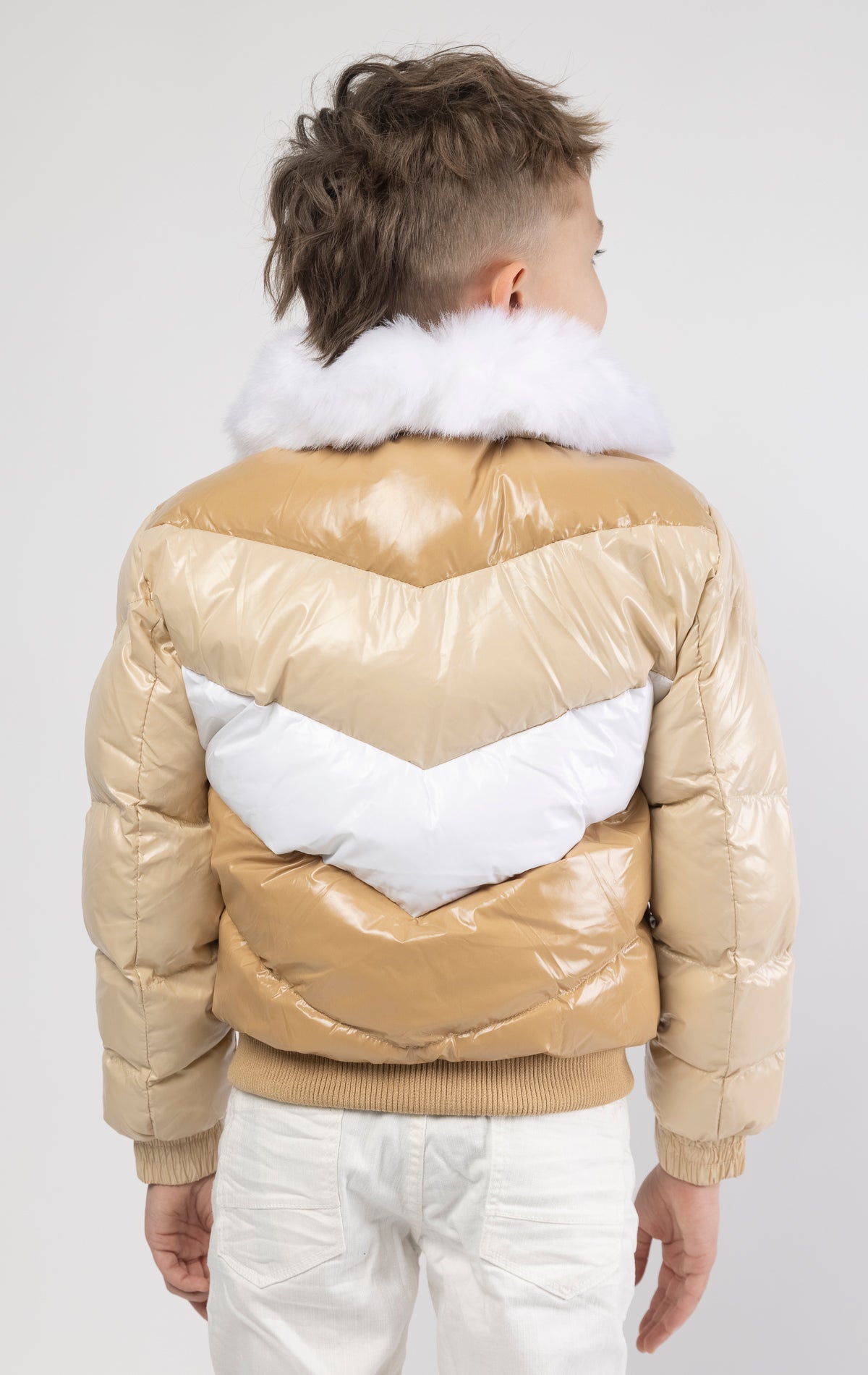 This kids' puffer jacket features a 100% nylon laqué shell, quilted padding, and 100% polyester lining. It also includes branded Jordan Craig zippers, dual side pockets with zipper closure, and a removable faux jackal fur collar.