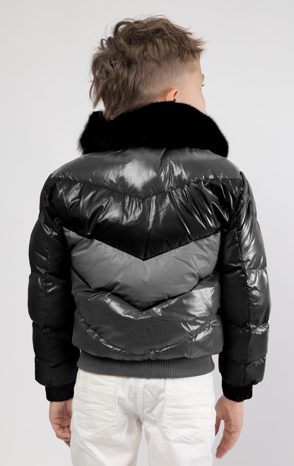 This kids' puffer jacket features a 100% nylon laqué shell, quilted padding, and 100% polyester lining. It also includes branded Jordan Craig zippers, dual side pockets with zipper closure, and a removable faux jackal fur collar.