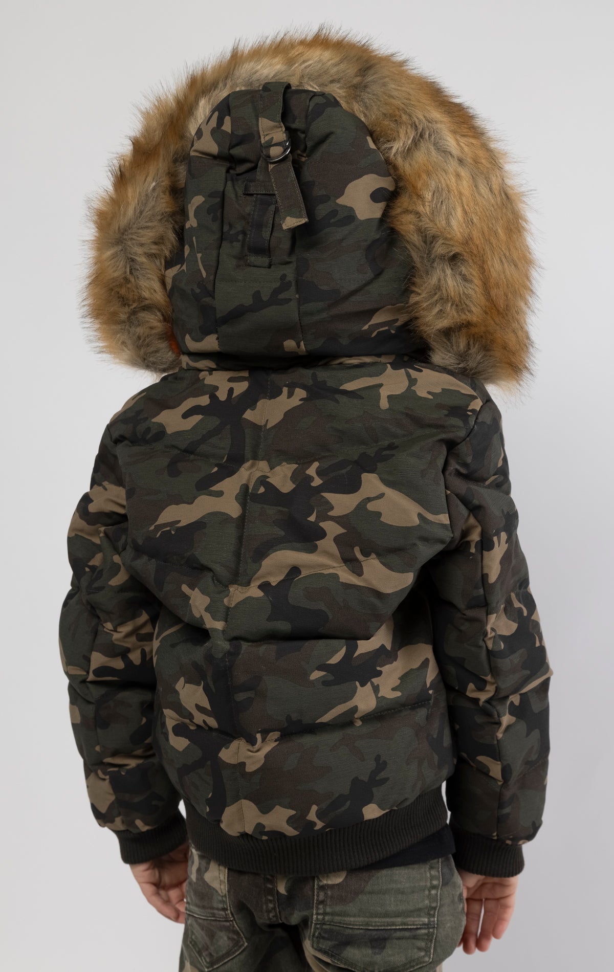 Full zip bomber jacket silhouette, with quilted padding and dense insulation for extreme warmth. Made with 100% polyester lining and featuring a removable faux jackal fur collar and hood. Available in woodland and black camo.