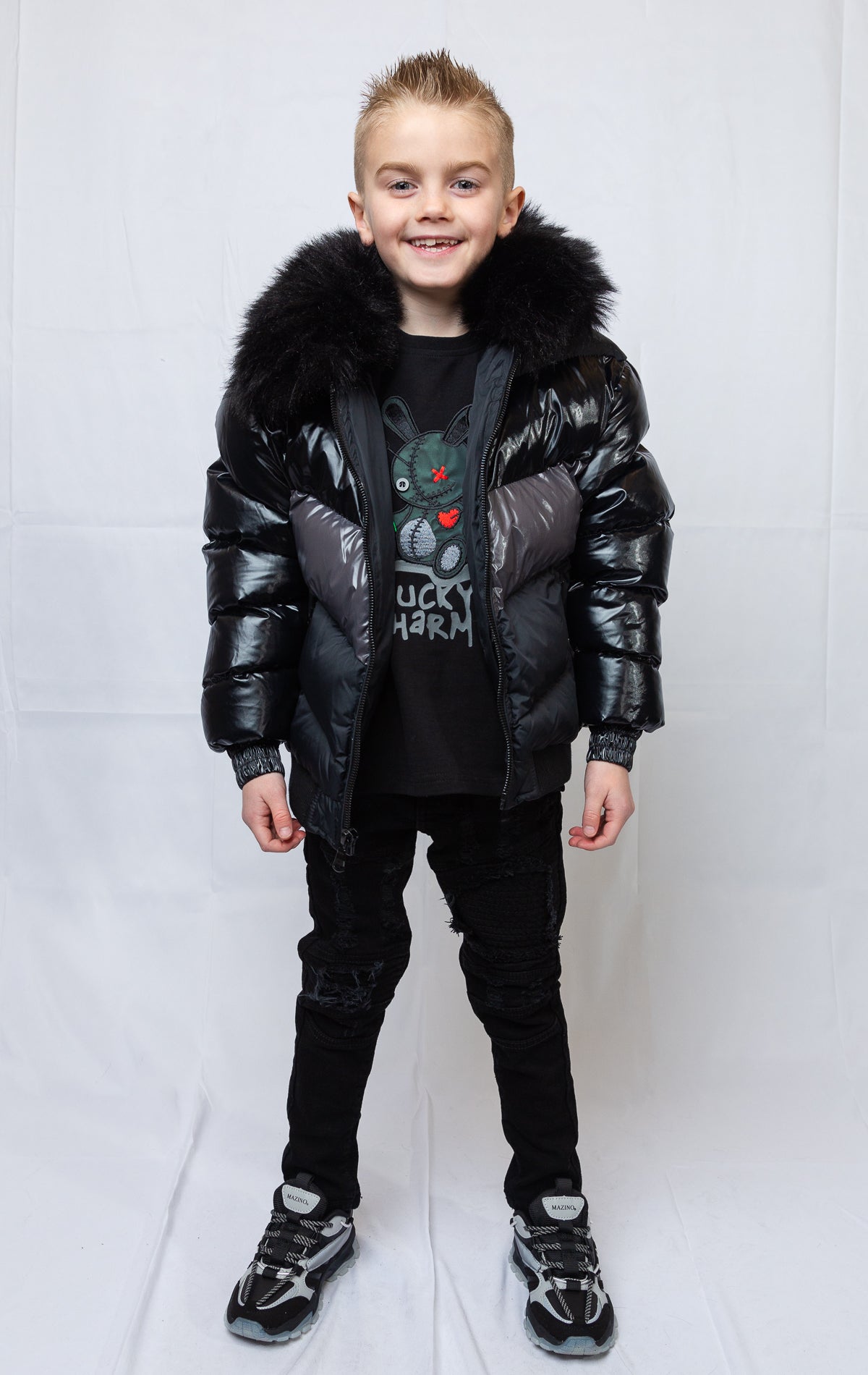 This kids' puffer jacket features a 100% nylon laqué shell, quilted padding, and 100% polyester lining. It also includes branded Jordan Craig zippers, dual side pockets with zipper closure, and a removable faux jackal fur collar.