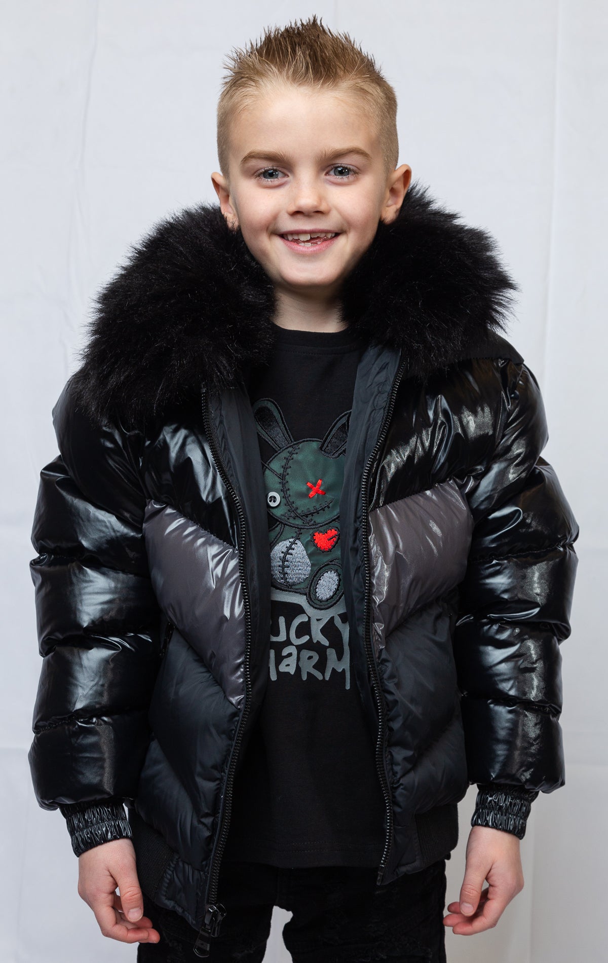 This kids' puffer jacket features a 100% nylon laqué shell, quilted padding, and 100% polyester lining. It also includes branded Jordan Craig zippers, dual side pockets with zipper closure, and a removable faux jackal fur collar.