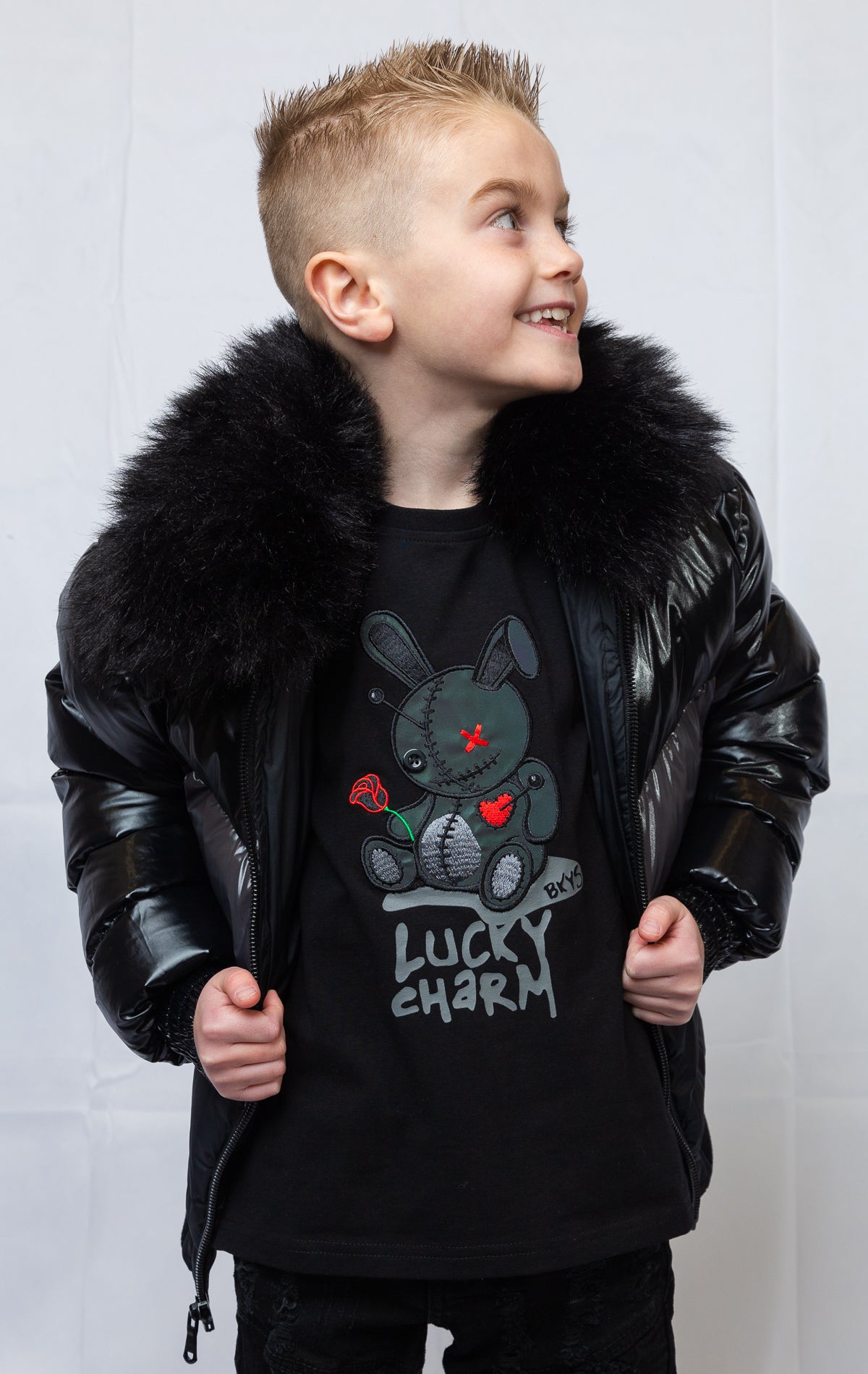 This kids' puffer jacket features a 100% nylon laqué shell, quilted padding, and 100% polyester lining. It also includes branded Jordan Craig zippers, dual side pockets with zipper closure, and a removable faux jackal fur collar.