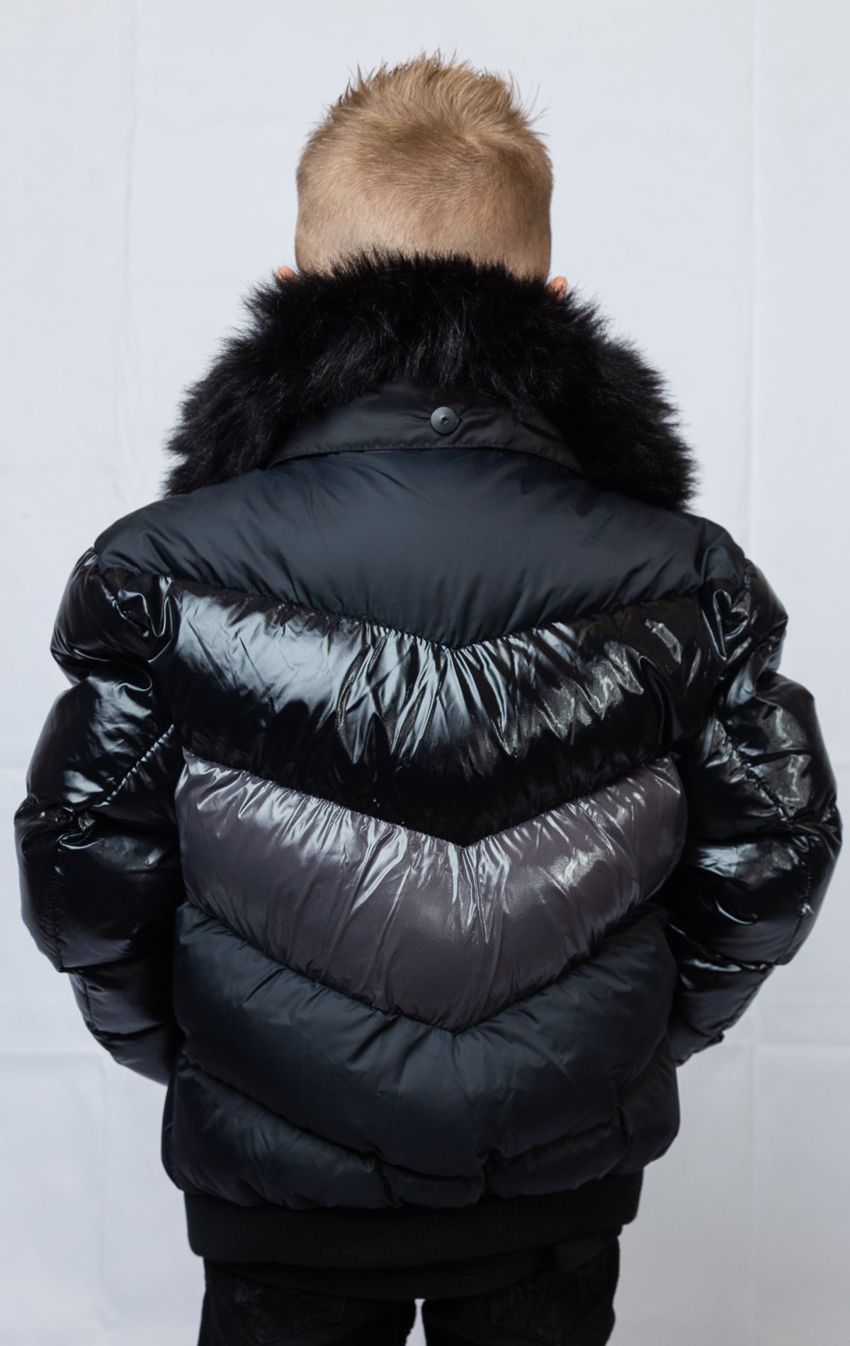 This kids' puffer jacket features a 100% nylon laqué shell, quilted padding, and 100% polyester lining. It also includes branded Jordan Craig zippers, dual side pockets with zipper closure, and a removable faux jackal fur collar.