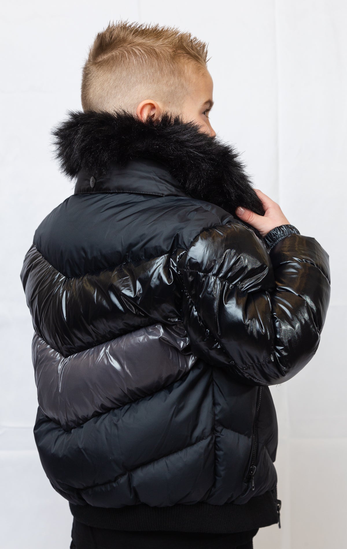 This kids' puffer jacket features a 100% nylon laqué shell, quilted padding, and 100% polyester lining. It also includes branded Jordan Craig zippers, dual side pockets with zipper closure, and a removable faux jackal fur collar.