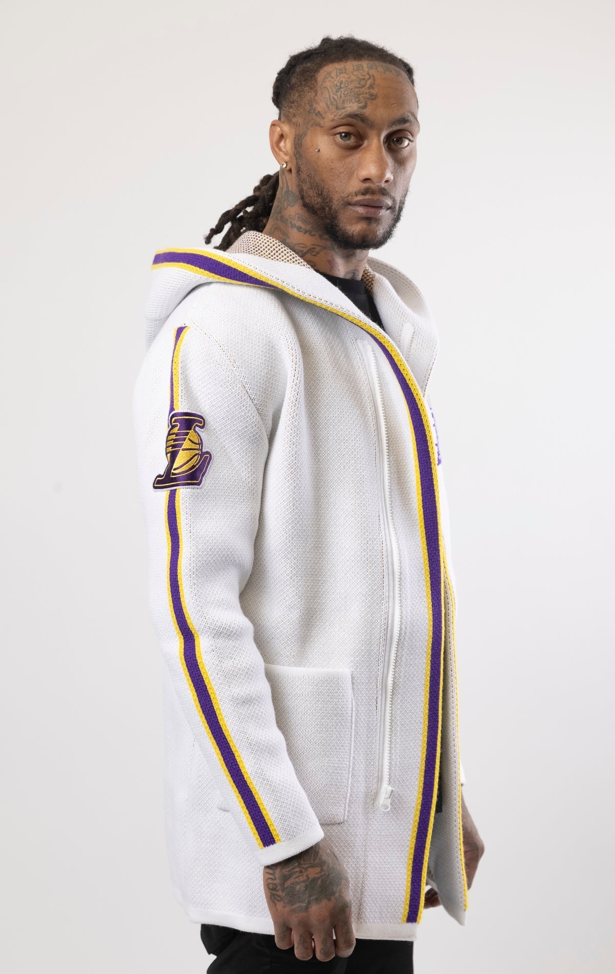 White LA LAKERS Cardigan Sweater. This cozy jacket is designed with a stylish three-quarter length and boasts bold team branding on the front, back, and sleeve. Complete with a full-zip closure, attached hood, and front pockets, this knit sweater offers b