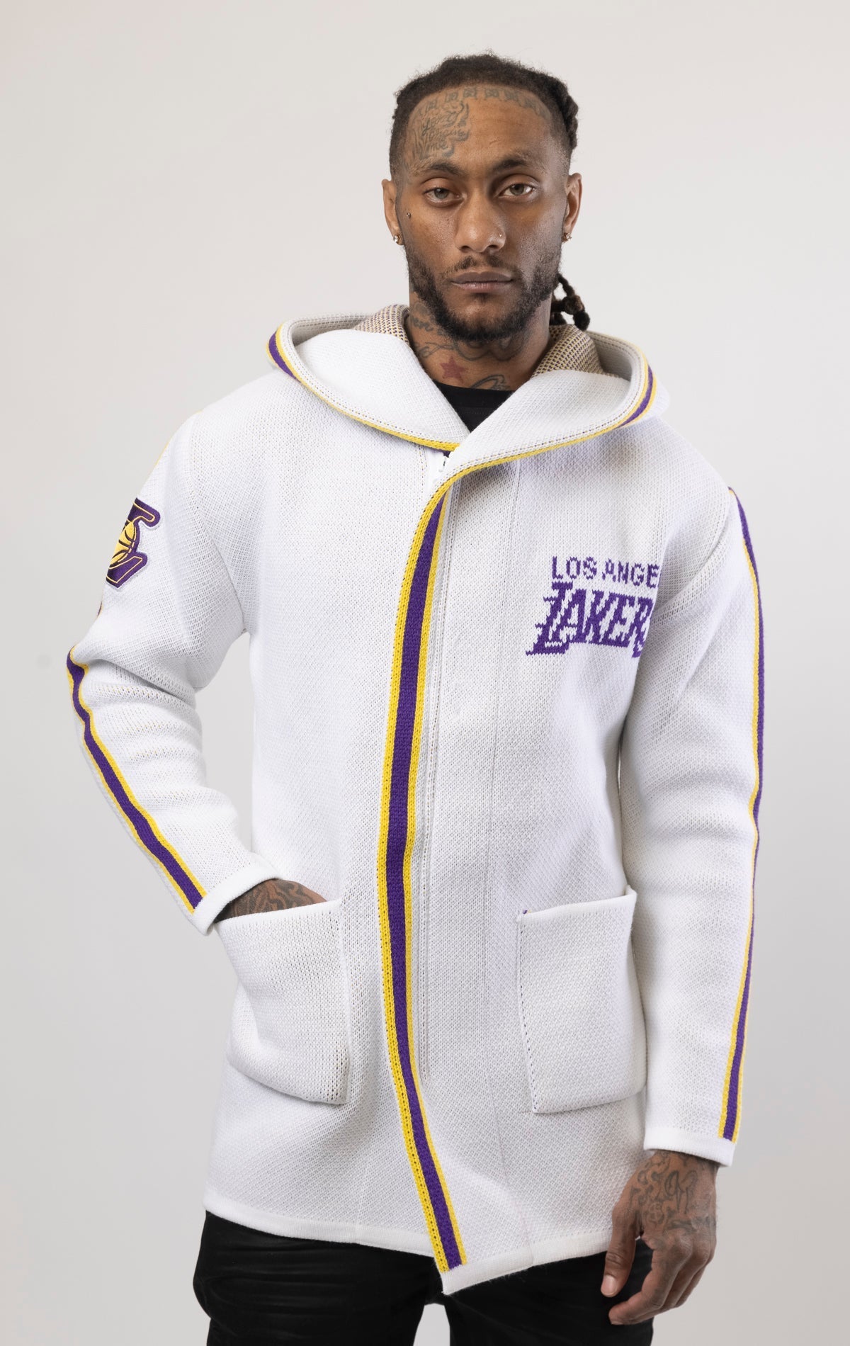 White LA LAKERS Cardigan Sweater. This cozy jacket is designed with a stylish three-quarter length and boasts bold team branding on the front, back, and sleeve. Complete with a full-zip closure, attached hood, and front pockets, this knit sweater offers b