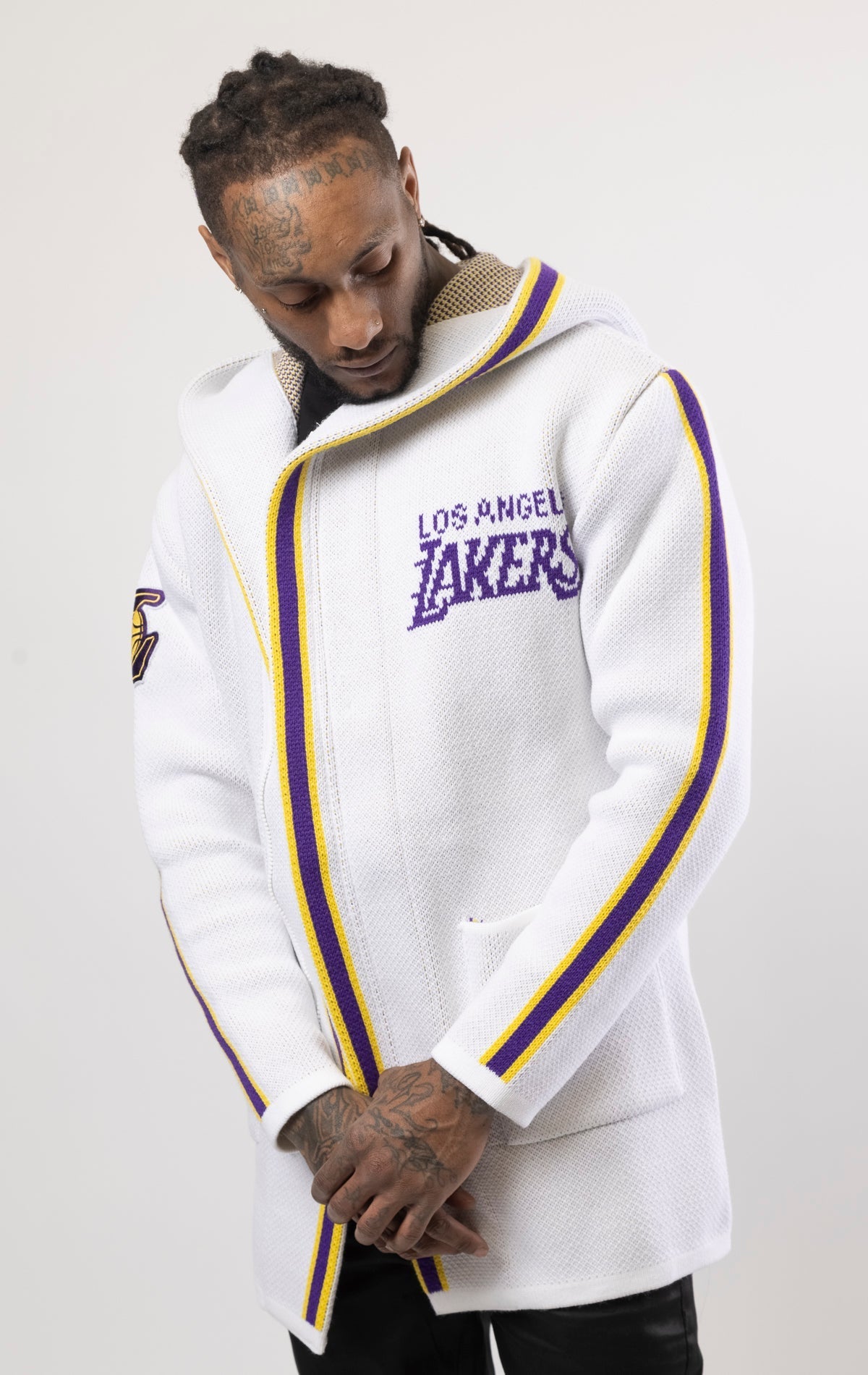 White LA LAKERS Cardigan Sweater. This cozy jacket is designed with a stylish three-quarter length and boasts bold team branding on the front, back, and sleeve. Complete with a full-zip closure, attached hood, and front pockets, this knit sweater offers b