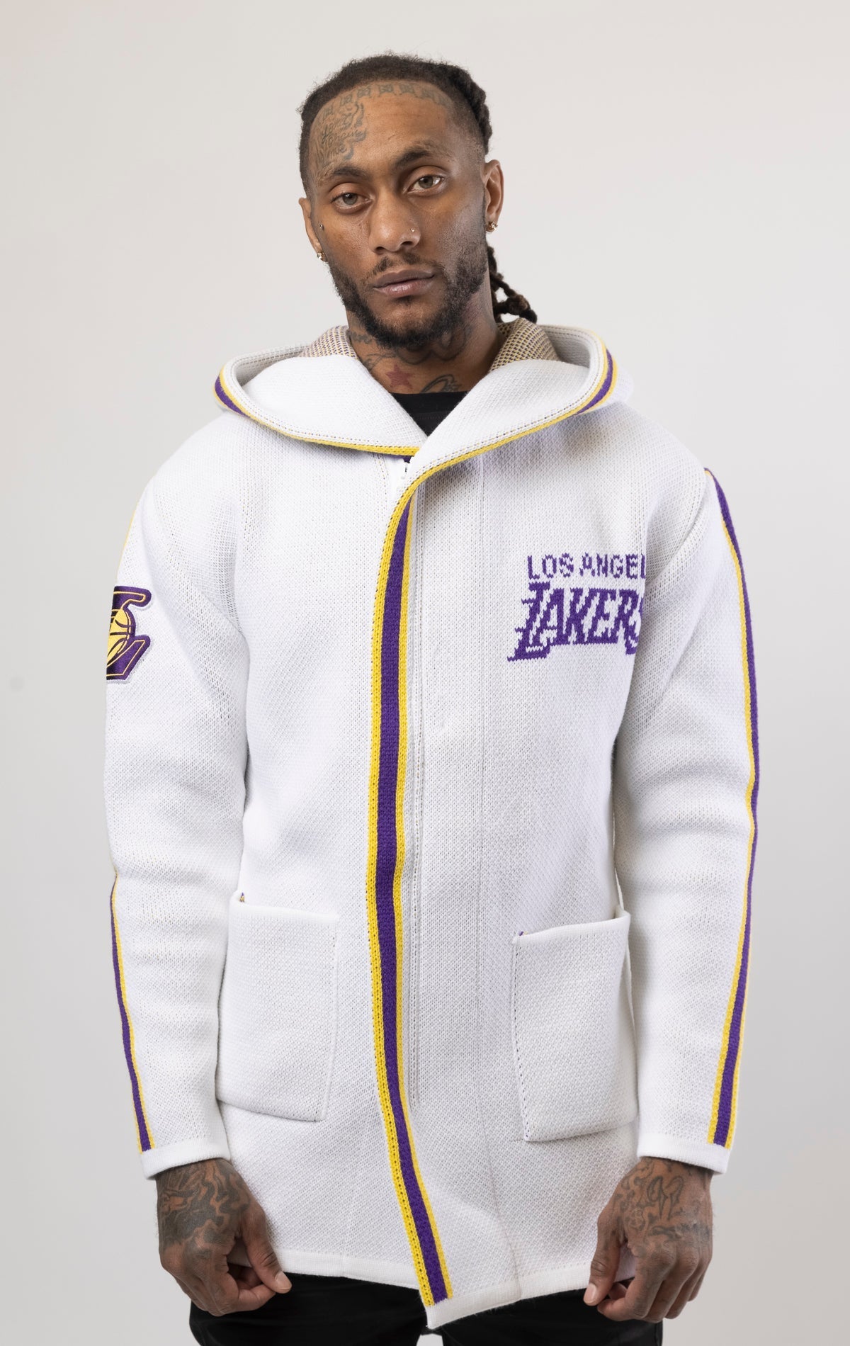 White LA LAKERS Cardigan Sweater. This cozy jacket is designed with a stylish three-quarter length and boasts bold team branding on the front, back, and sleeve. Complete with a full-zip closure, attached hood, and front pockets, this knit sweater offers b