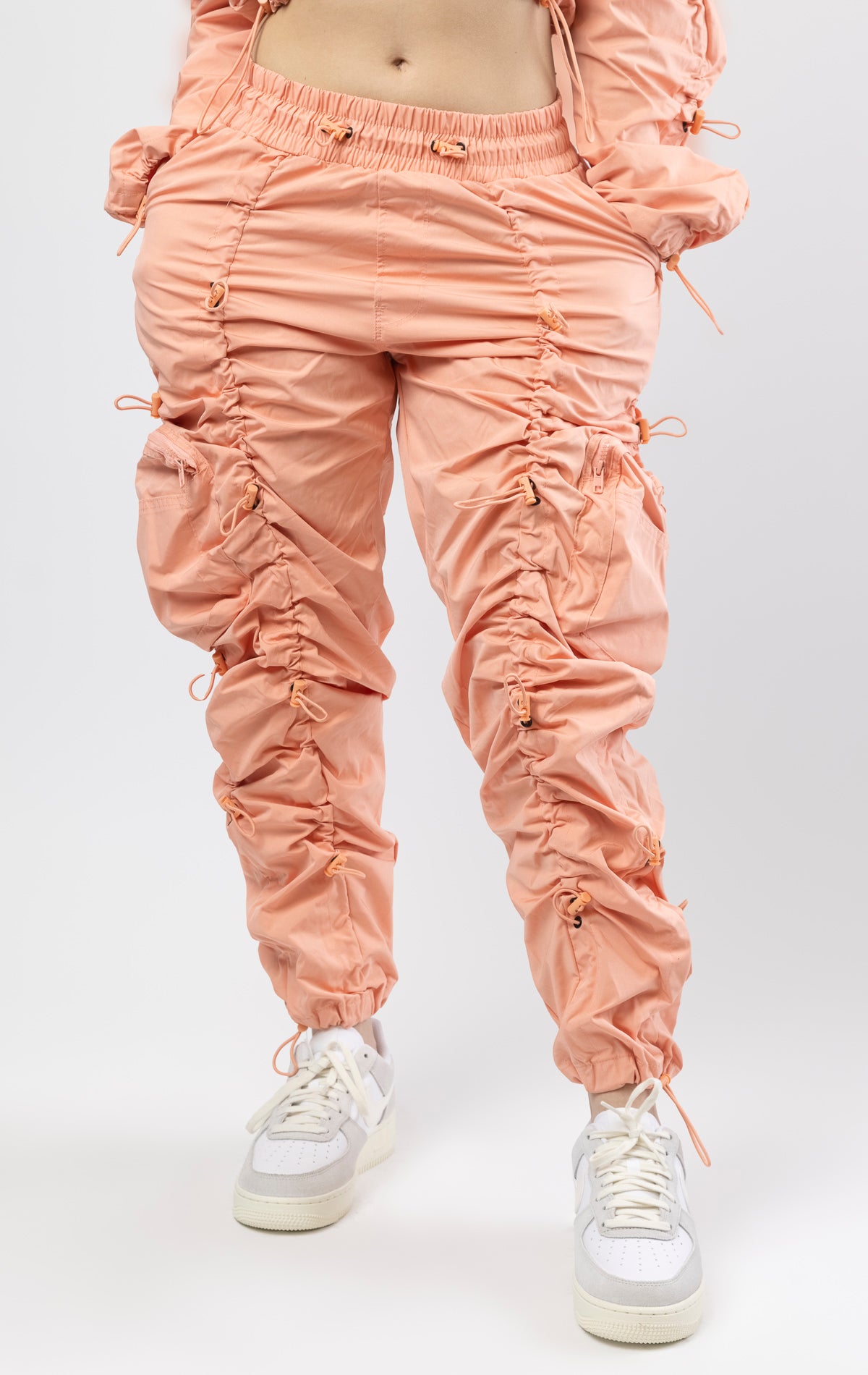 Sand coral multi-bungee jogger featuring a Brook fit, snap buttons, an adjustable waist and wide pockets.