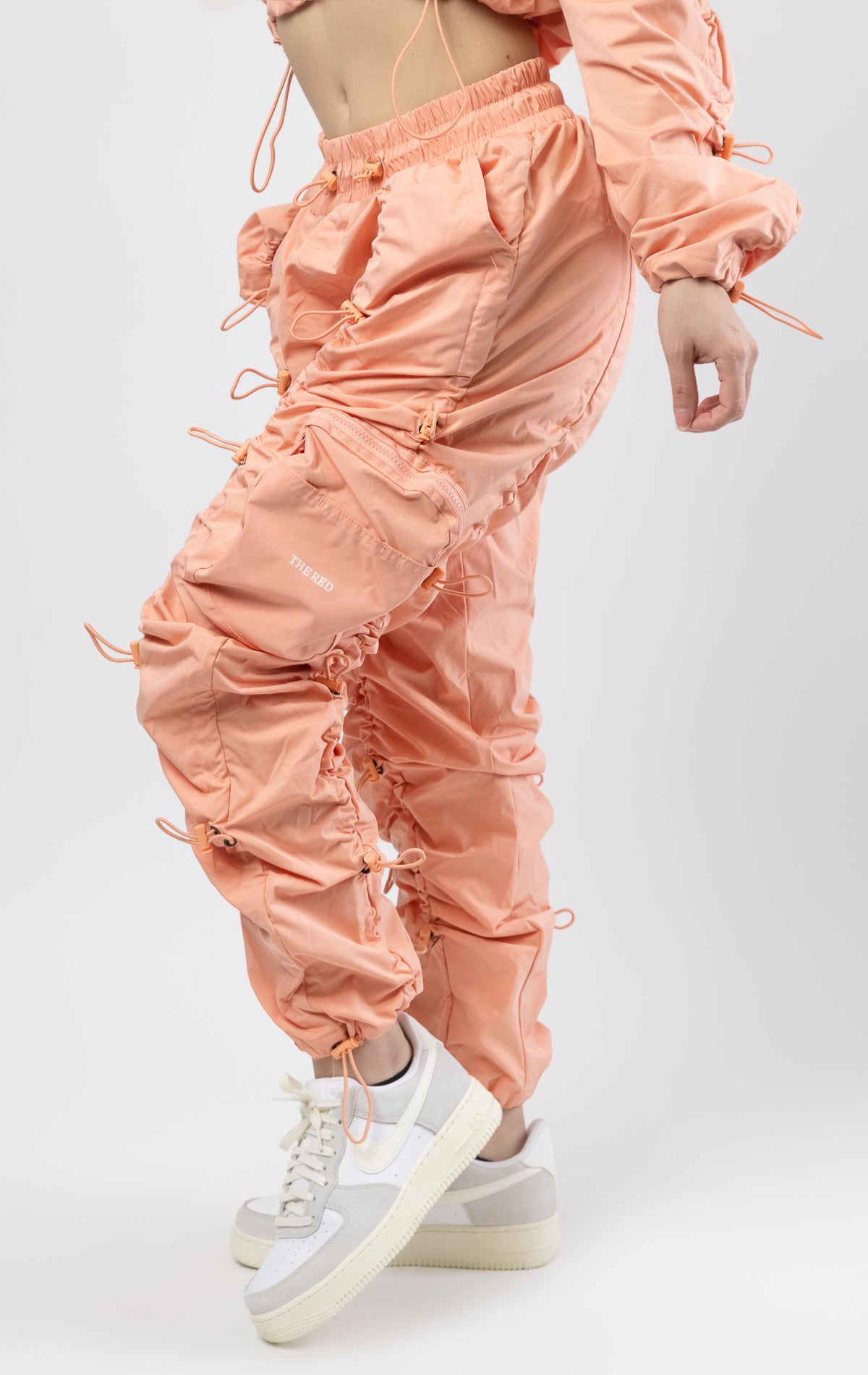 Sand coral multi-bungee jogger featuring a Brook fit, snap buttons, an adjustable waist and wide pockets.