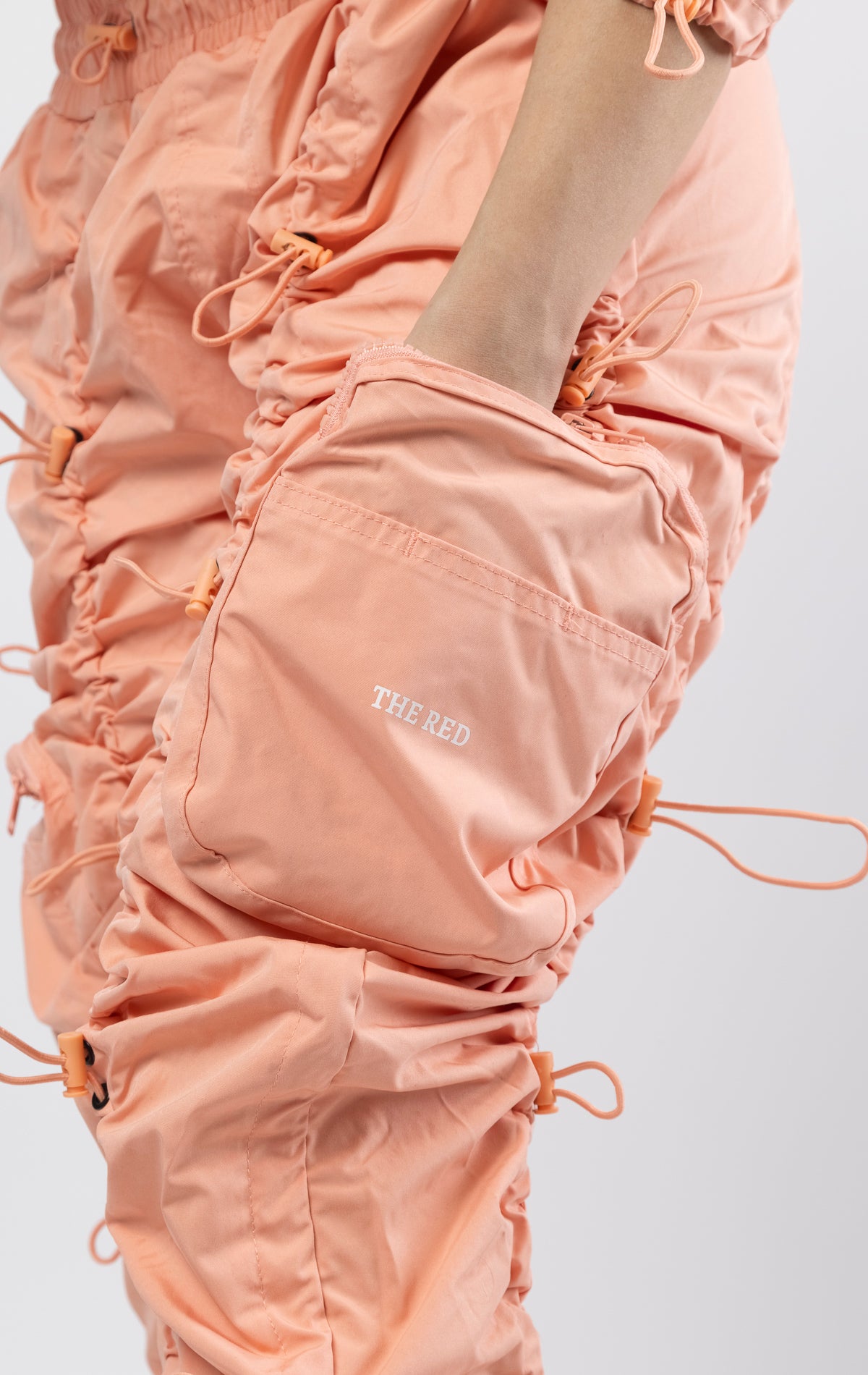 Sand coral multi-bungee jogger featuring a Brook fit, snap buttons, an adjustable waist and wide pockets.