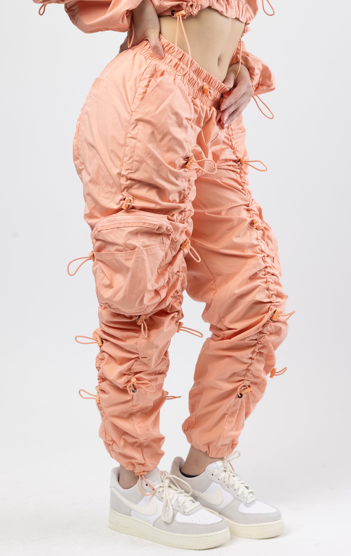 Sand coral multi-bungee jogger featuring a Brook fit, snap buttons, an adjustable waist and wide pockets.