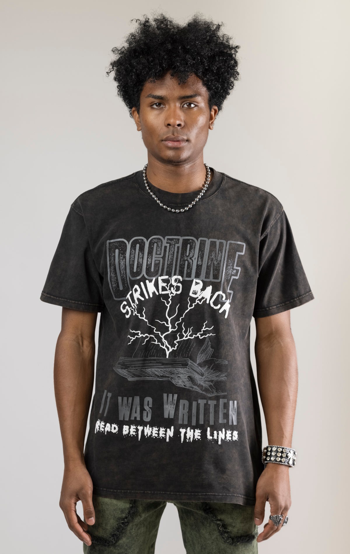 A DOCTRINE STRIKE BACK T-shirt featuring a high-definition digital graphic print across the front. The shirt is made from 100% cotton and has a vintage-washed look.
