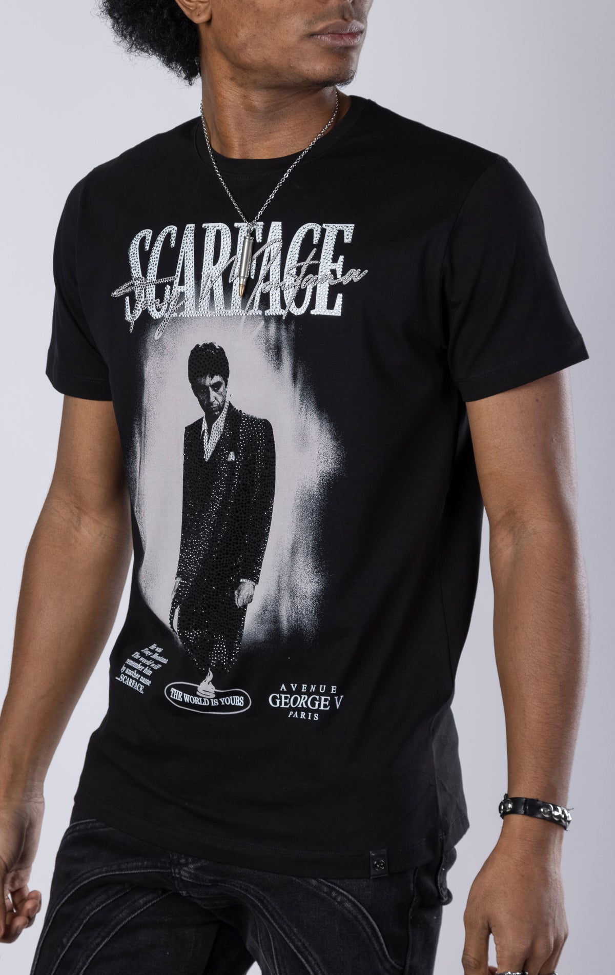 black Scarface Crewneck Tee. Features a crewneck, short sleeves, and a bold Scarface graphic. Made from a blend of 95% cotton and 5% lycra.