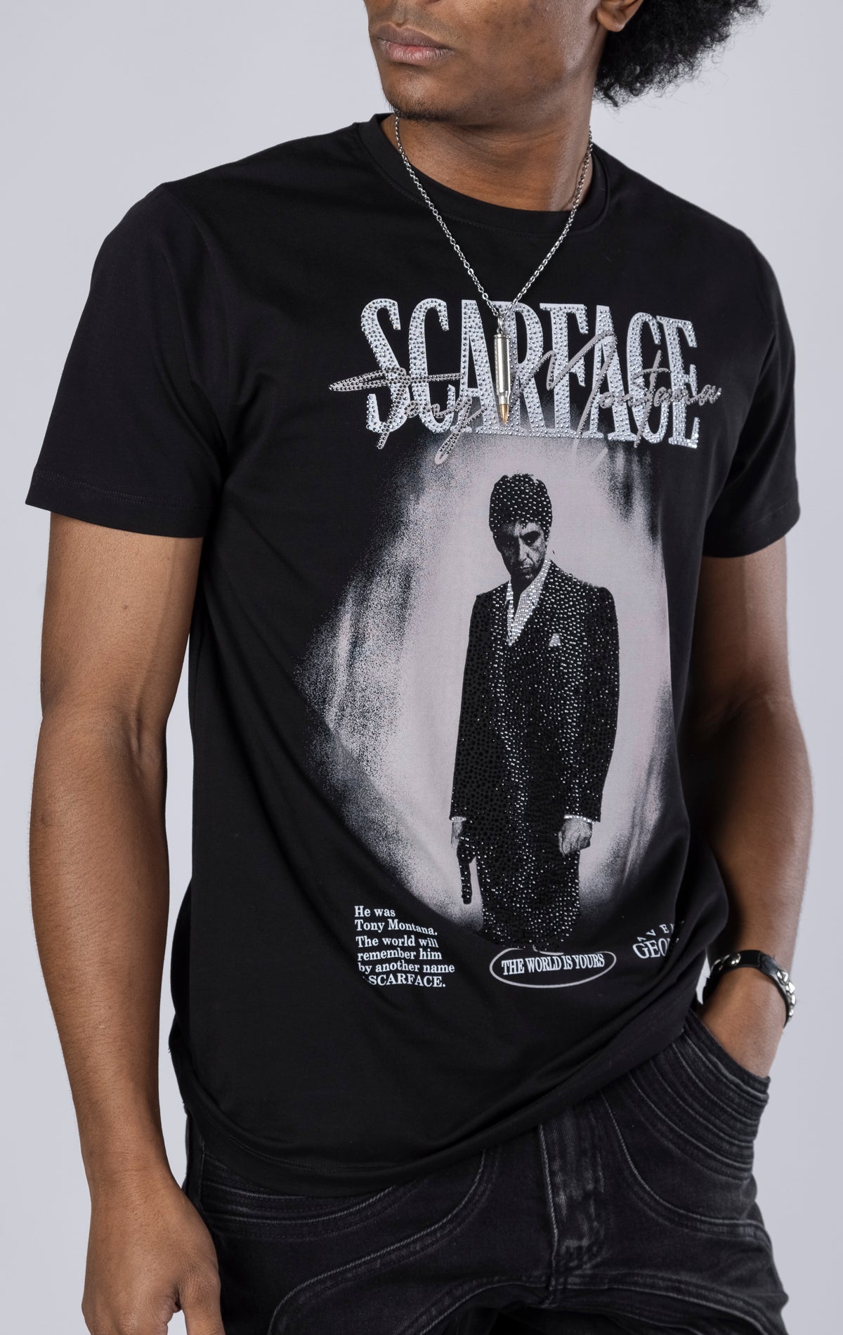 black Scarface Crewneck Tee. Features a crewneck, short sleeves, and a bold Scarface graphic. Made from a blend of 95% cotton and 5% lycra.