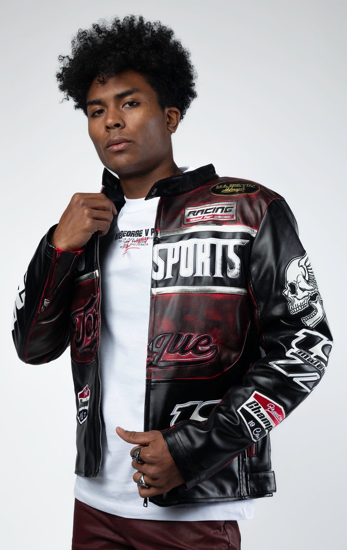 Black motor sport racing jacket with snap-button collar, full zip-up closure, multi-patch and embroidered details, zippered sleeves and pockets, and elasticized ribbed collar, cuffs, and waist. The interior includes a hanger loop, welt pocket, and faux le