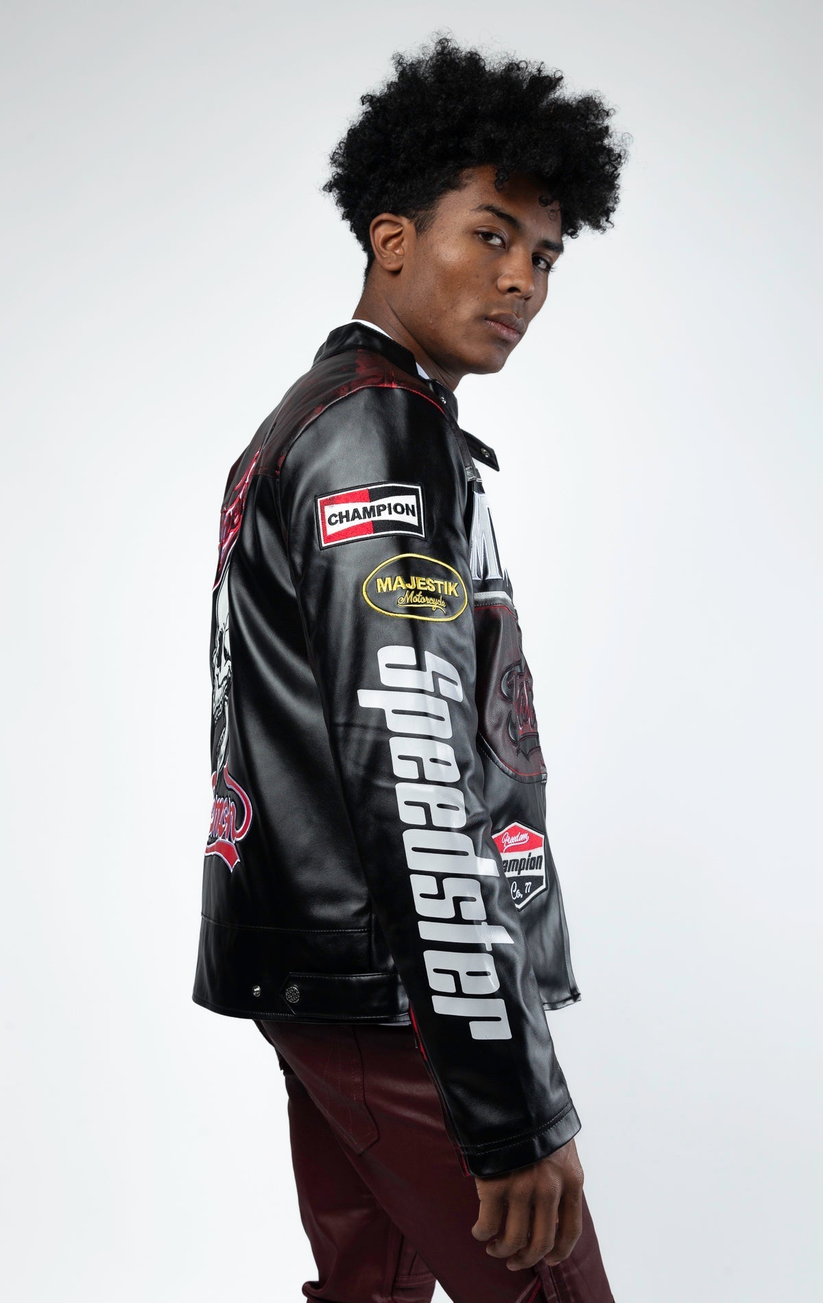 Black motor sport racing jacket with snap-button collar, full zip-up closure, multi-patch and embroidered details, zippered sleeves and pockets, and elasticized ribbed collar, cuffs, and waist. The interior includes a hanger loop, welt pocket, and faux le