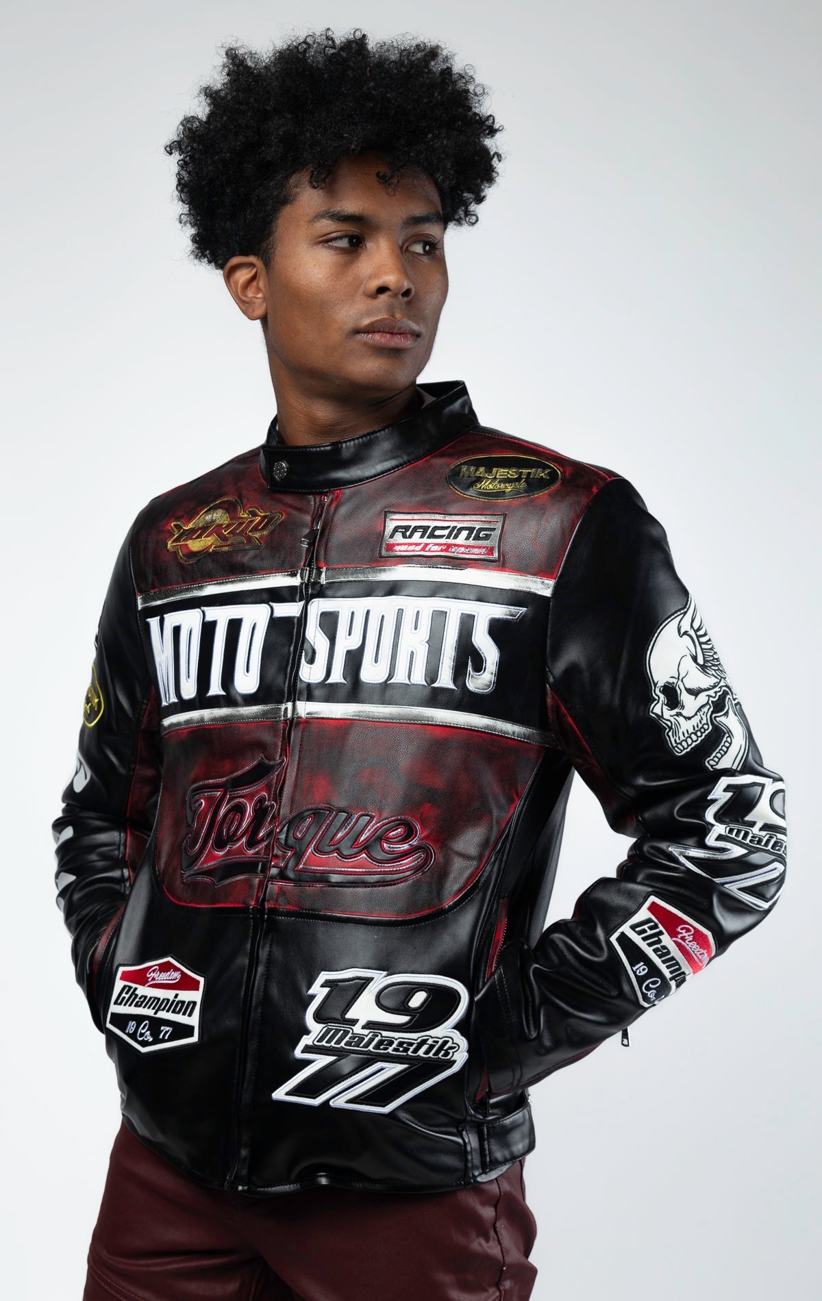 Black motor sport racing jacket with snap-button collar, full zip-up closure, multi-patch and embroidered details, zippered sleeves and pockets, and elasticized ribbed collar, cuffs, and waist. The interior includes a hanger loop, welt pocket, and faux le