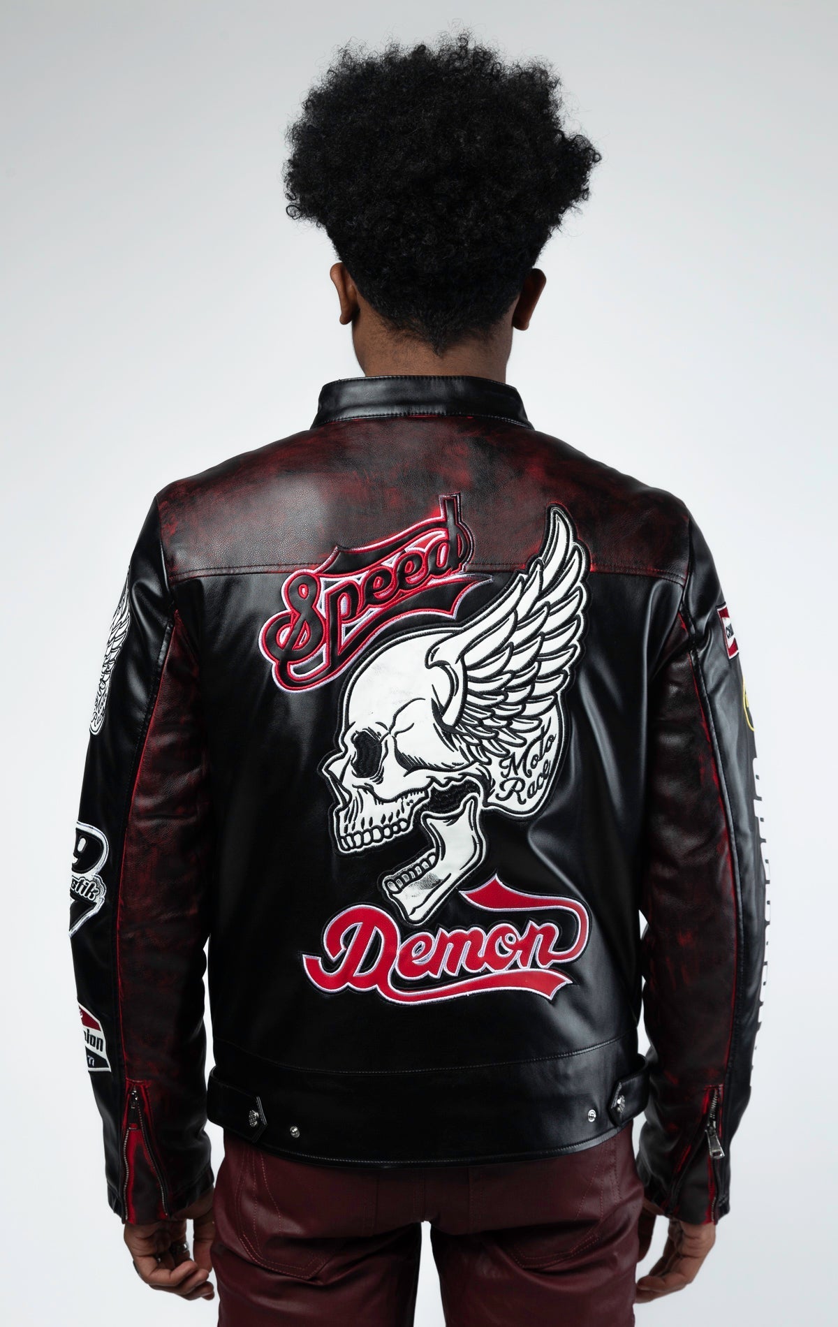 Black motor sport racing jacket with snap-button collar, full zip-up closure, multi-patch and embroidered details, zippered sleeves and pockets, and elasticized ribbed collar, cuffs, and waist. The interior includes a hanger loop, welt pocket, and faux le