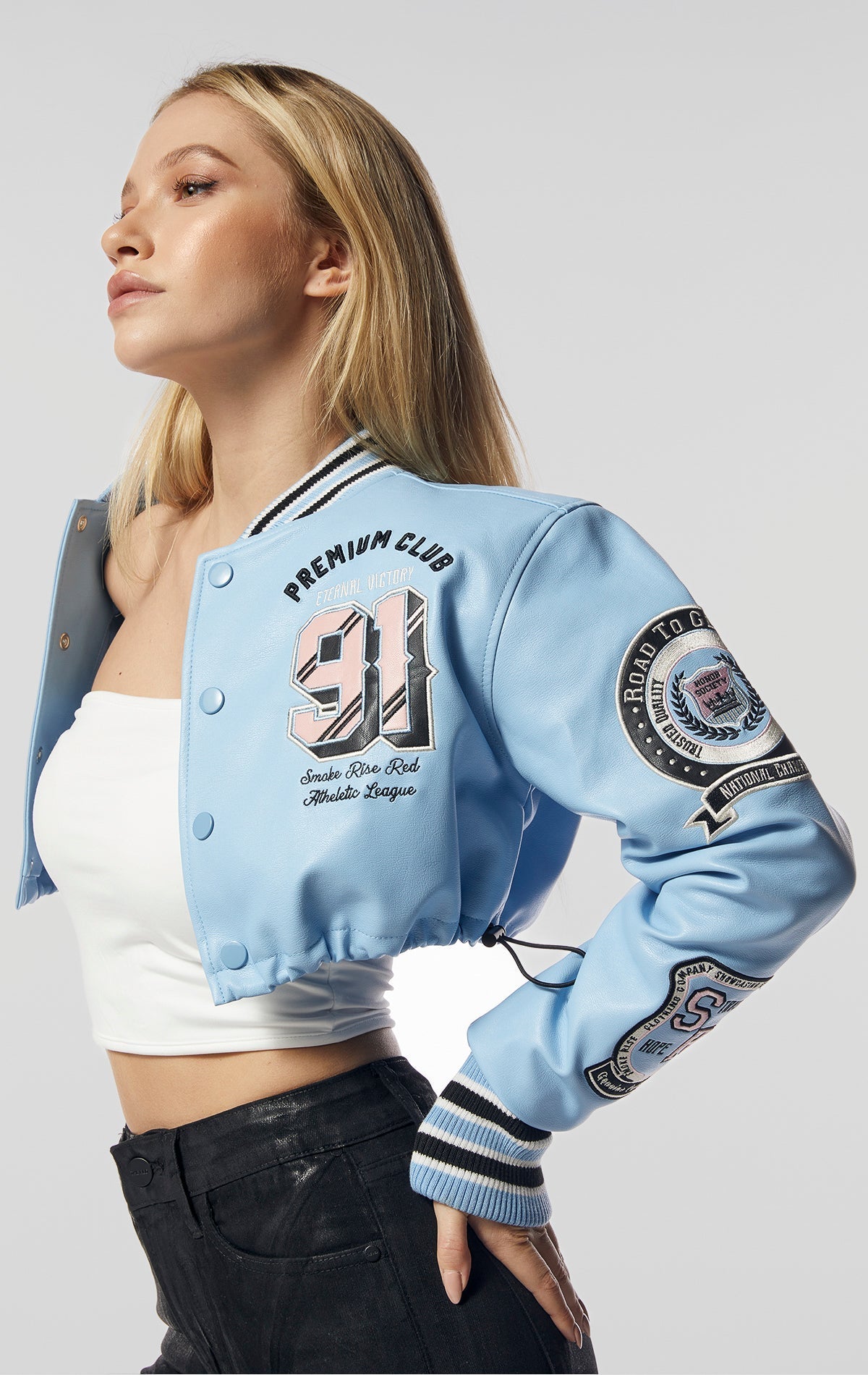 A fitted crop body, soft fabric shell, and quilting inside make up this women's varsity jacket. With its cotton span rib, twill, embo, and 3D patches, it's a stylish and comfortable addition to any wardrobe. The adjustable bottom opening, complete with bu