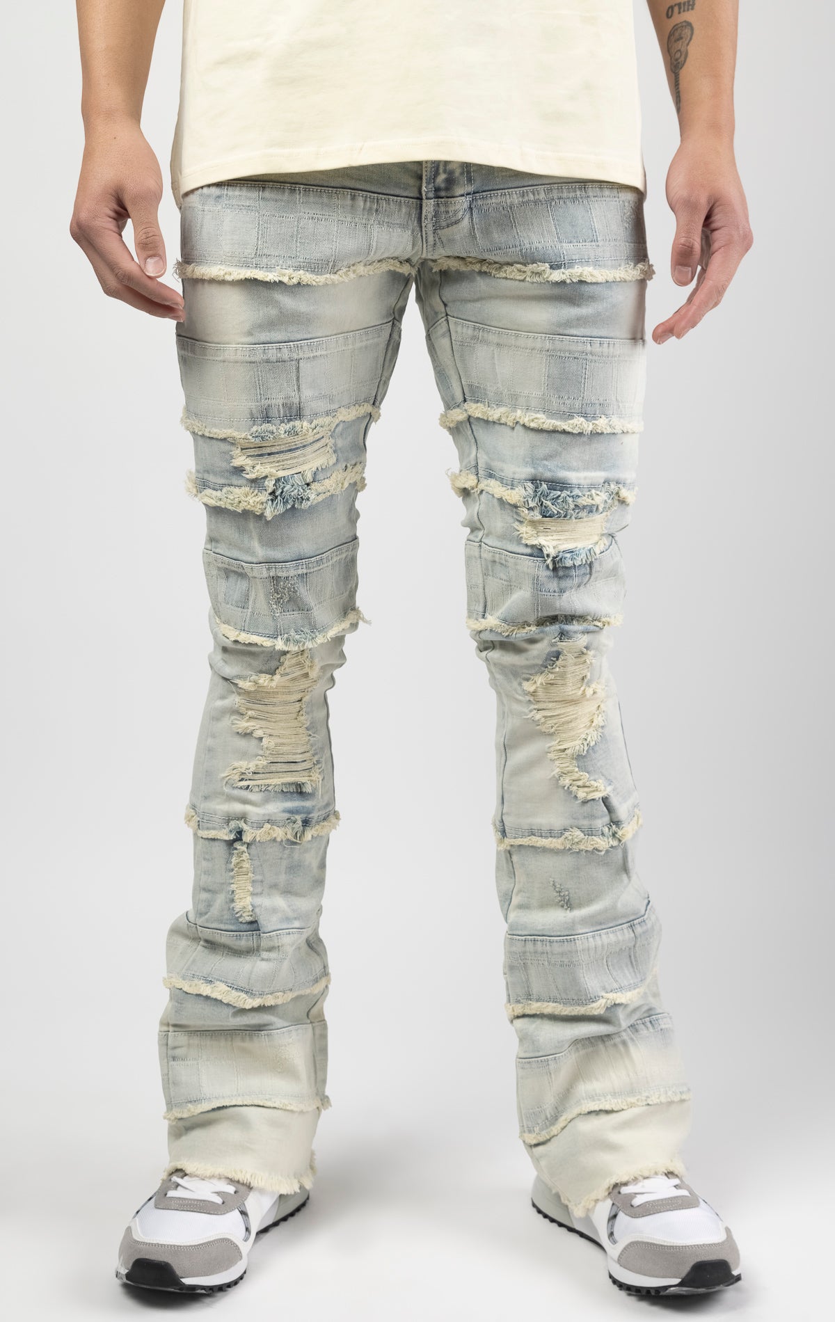 Light wash iconic stacked jeans crafted from high-quality, durable denim fabric consisting of 98% cotton and 2% spandex with a semi flare silhouette and a length of 35"-37". Featuring a distinctive ripped and repair design with pocket patches and a multi-tone dye throughout, these urban-inspired pants are true to size