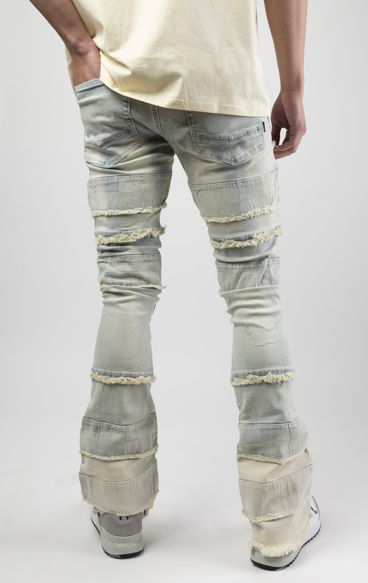 Light wash iconic stacked jeans crafted from high-quality, durable denim fabric consisting of 98% cotton and 2% spandex with a semi flare silhouette and a length of 35"-37". Featuring a distinctive ripped and repair design with pocket patches and a multi-tone dye throughout, these urban-inspired pants are true to size