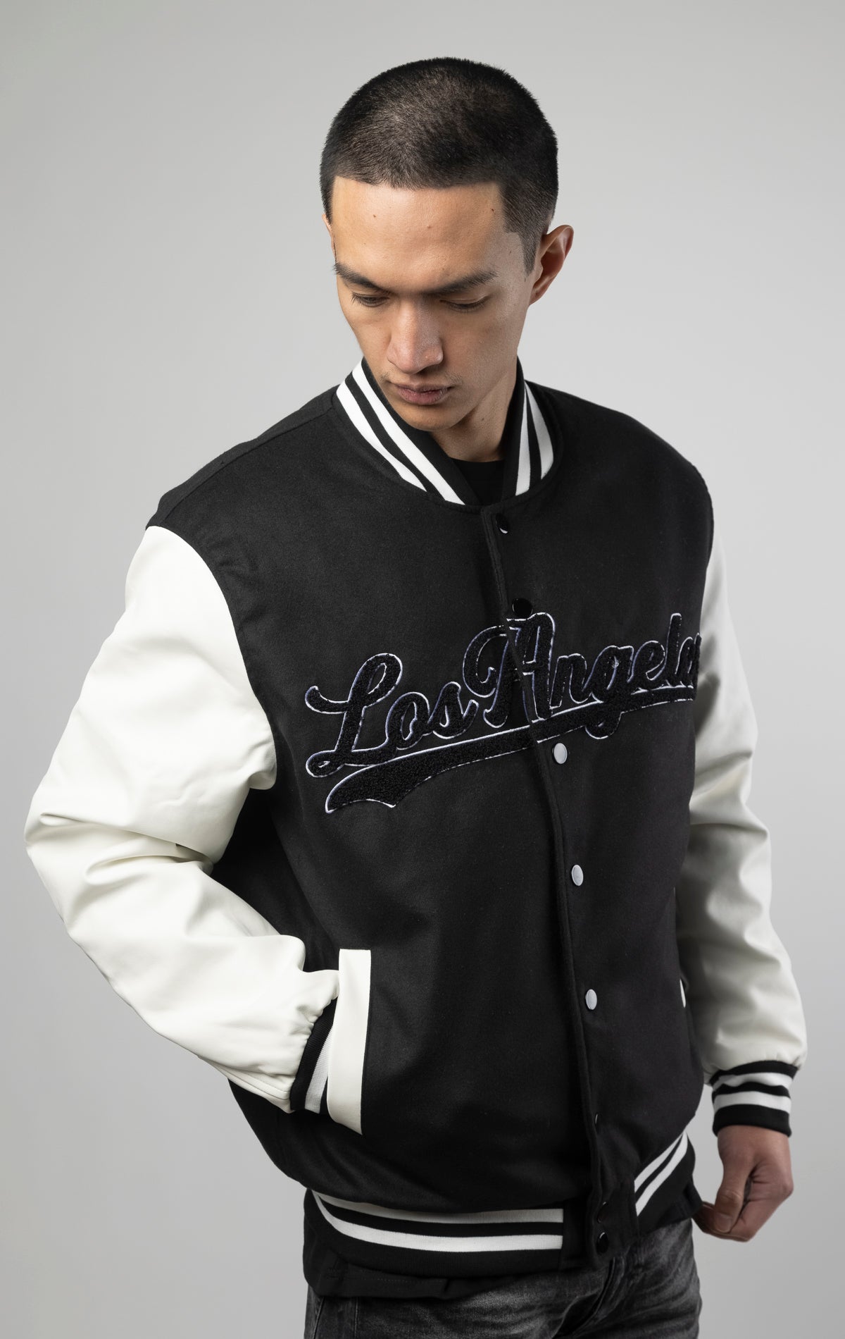 Black and white Los Angeles varsity jacket featuring a sleek button closure, ribbed cuffs, and a satin lining for added comfort.