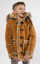 Cognac jacket lined with plush faux shearling throughout the body and sleeves. It also features shearling-accented pockets, a horn toggle front closure, and vegan suede straps with a buckle at the neck. For added convenience, a detachable faux fox fur hoo