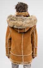 Cognac jacket lined with plush faux shearling throughout the body and sleeves. It also features shearling-accented pockets, a horn toggle front closure, and vegan suede straps with a buckle at the neck. For added convenience, a detachable faux fox fur hood with a zipper is included. This product is also available for adults.