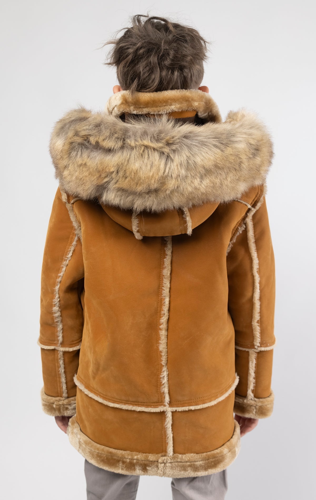 Cognac jacket lined with plush faux shearling throughout the body and sleeves. It also features shearling-accented pockets, a horn toggle front closure, and vegan suede straps with a buckle at the neck. For added convenience, a detachable faux fox fur hoo