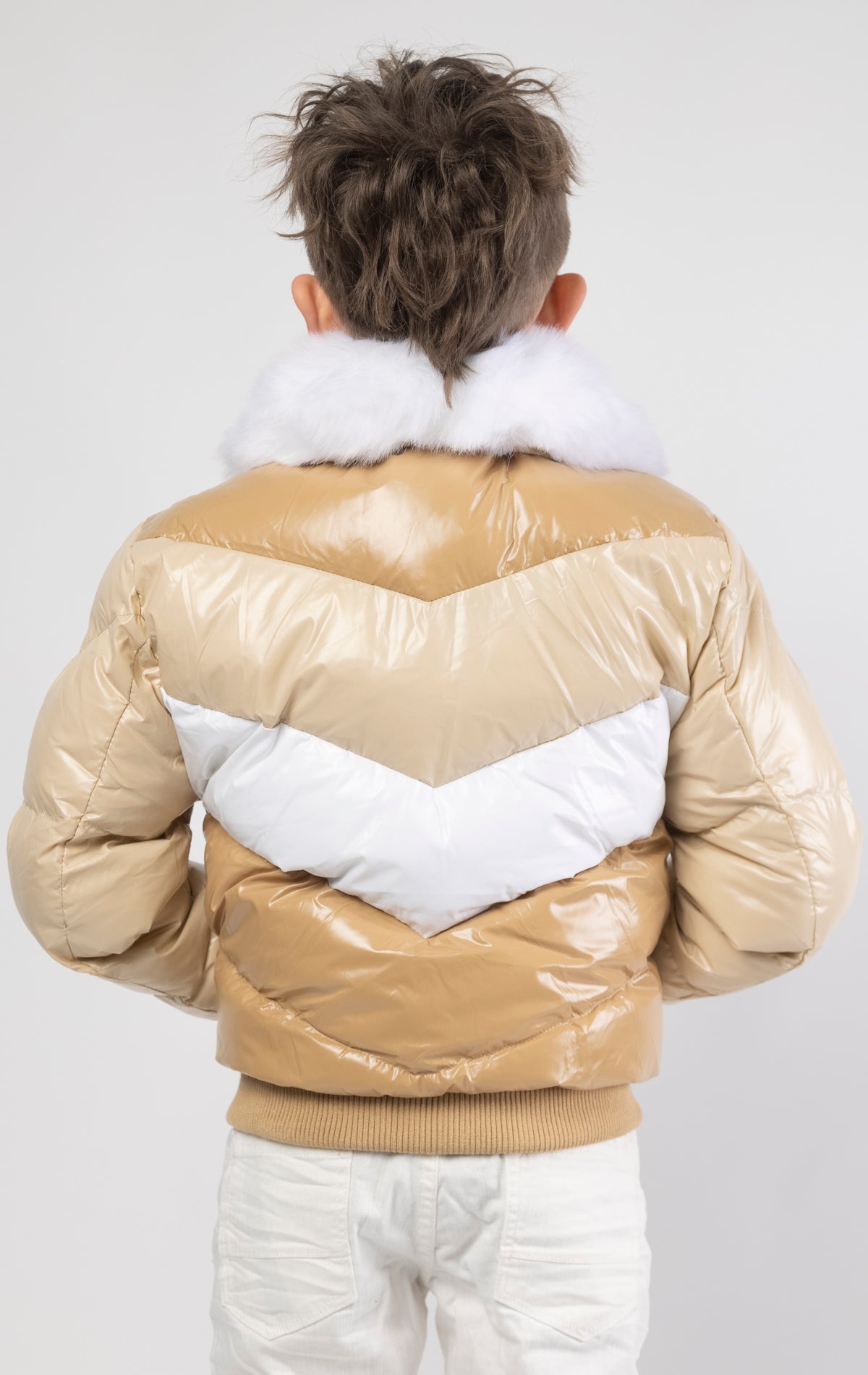 This kids' puffer jacket features a 100% nylon laqué shell, quilted padding, and 100% polyester lining. It also includes branded Jordan Craig zippers, dual side pockets with zipper closure, and a removable faux jackal fur collar.