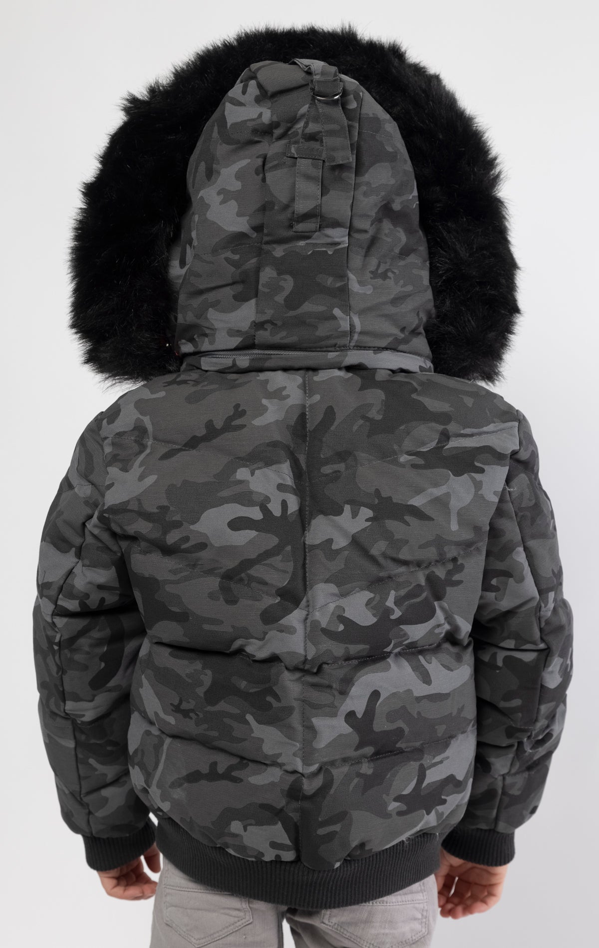Full zip bomber jacket silhouette, with quilted padding and dense insulation for extreme warmth. Made with 100% polyester lining and featuring a removable faux jackal fur collar and hood. Available in woodland and black camo.