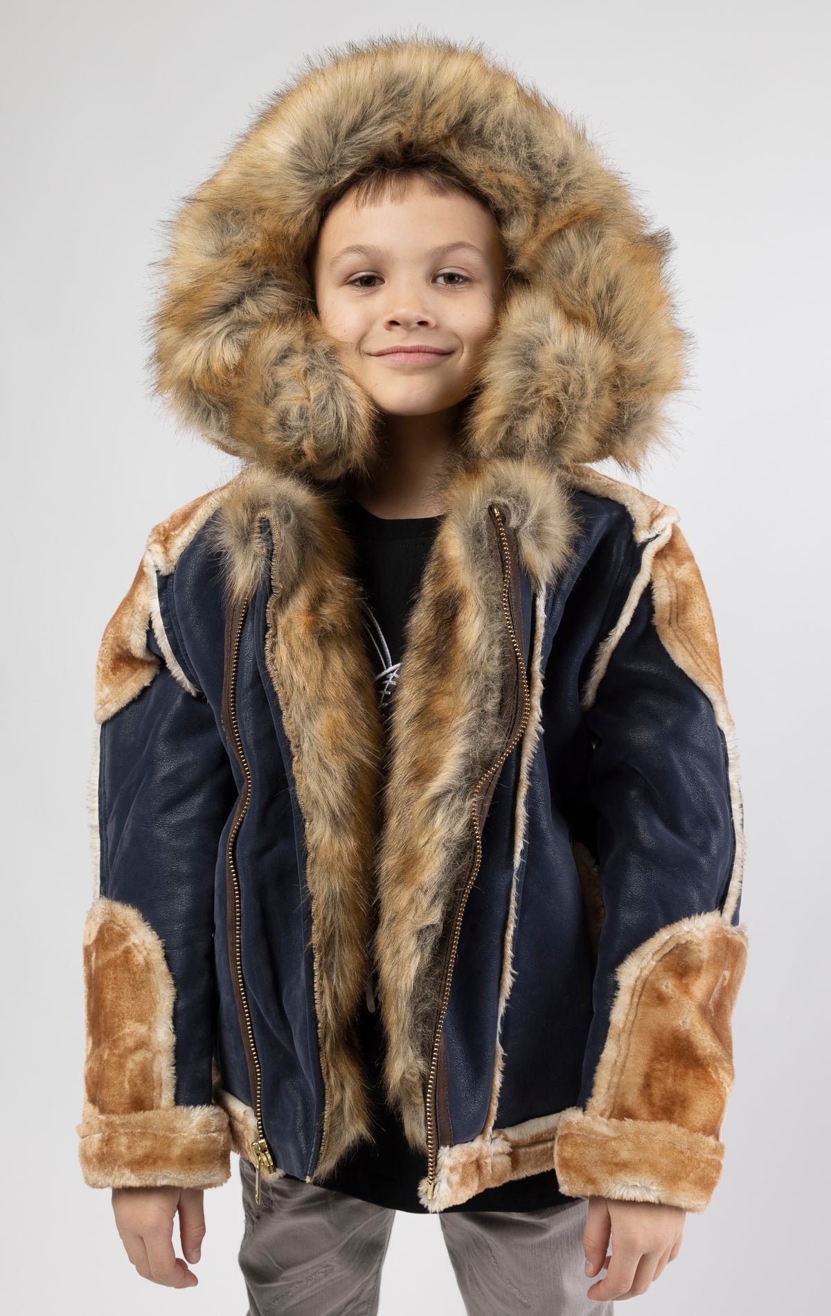 Faux suede body. Soft faux shearling lining on the body, sleeves, and pockets. Toggle front closure with vegan suede straps and a buckle at the neck. Detachable hood made of faux fox fur with a zipper.