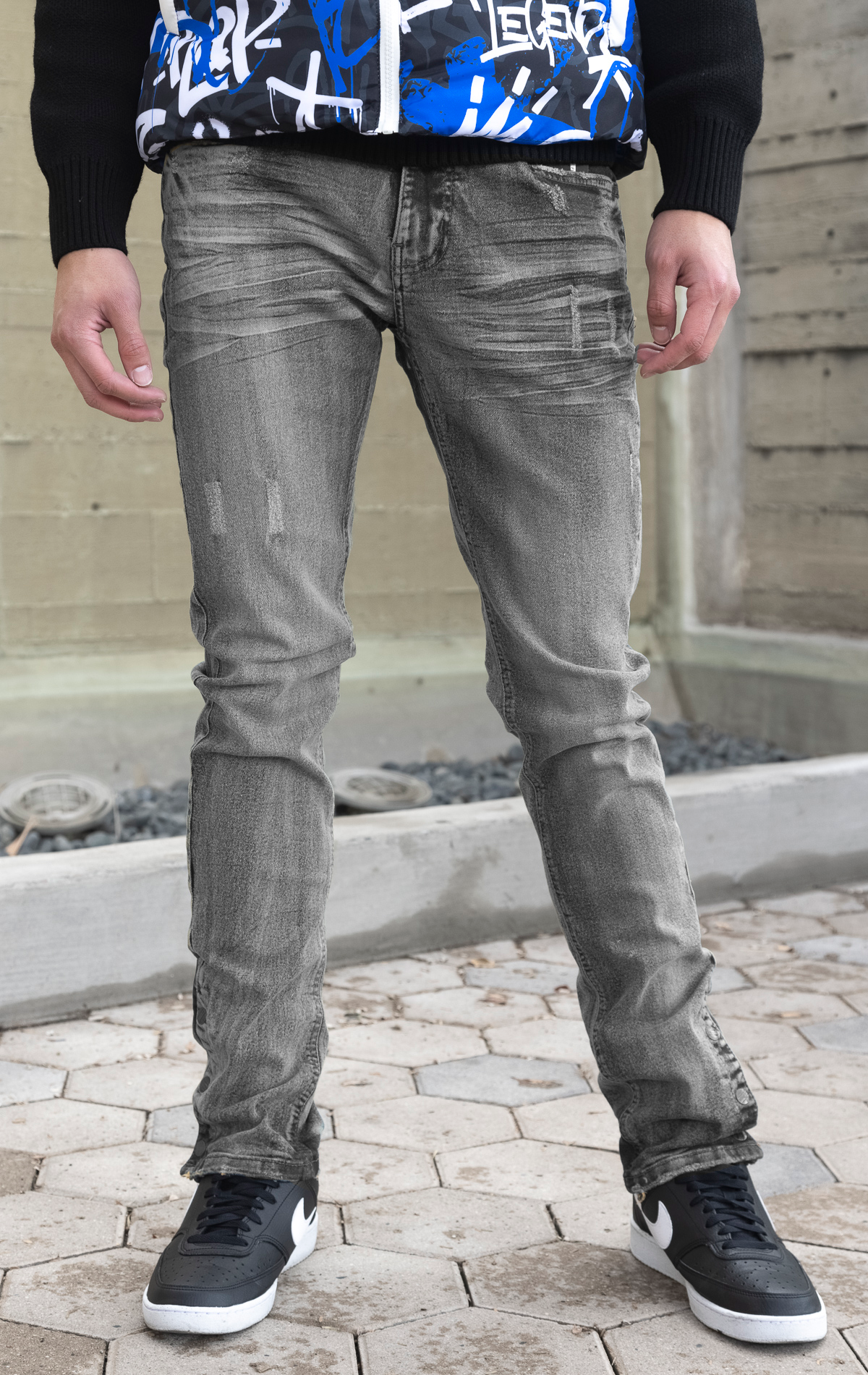 Grey denim featuring distressed detailing throughout, a skinny fit, stretch denim, and a buttoned flare.