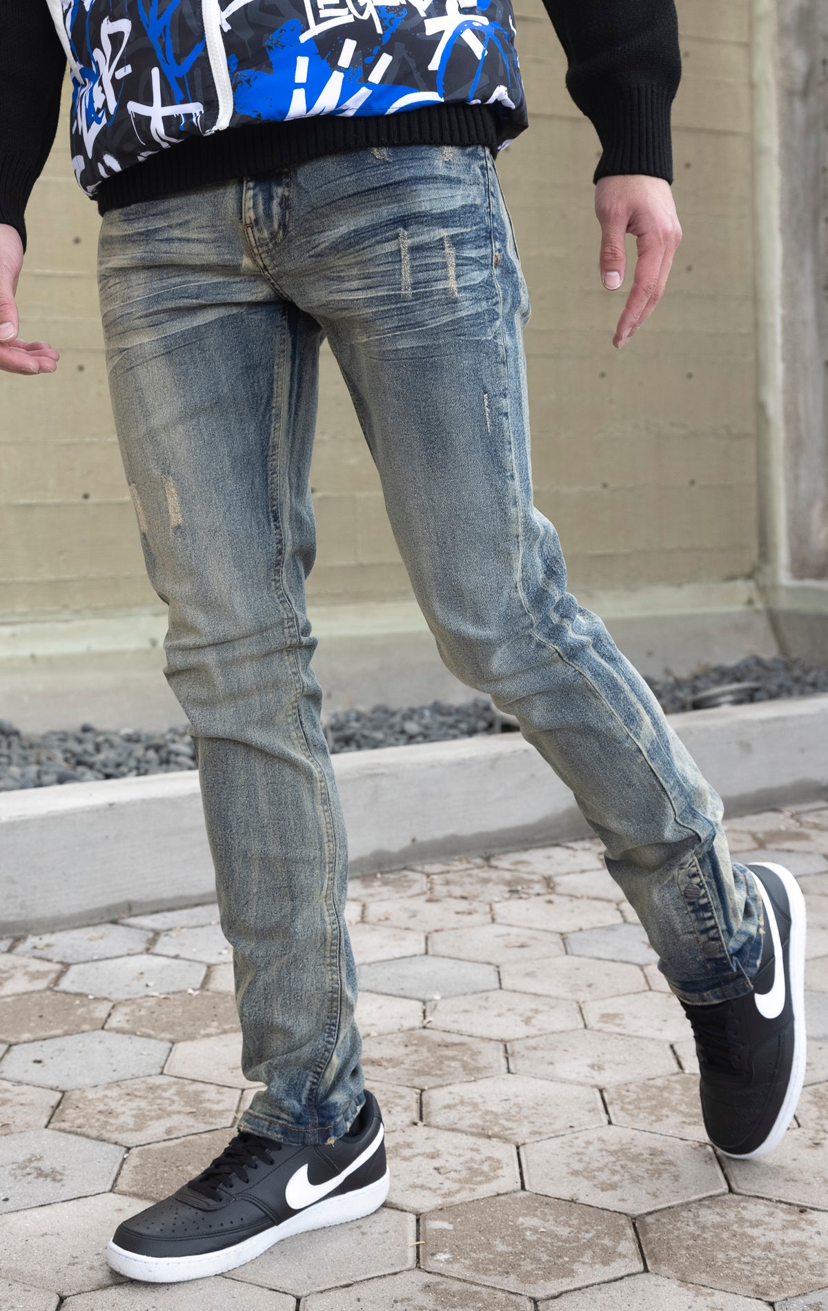 Light tint denim featuring distressed detailing throughout, a skinny fit, stretch denim, and a buttoned flare.