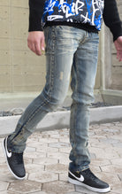 Light tint denim featuring distressed detailing throughout, a skinny fit, stretch denim, and a buttoned flare.
