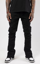 Jet black distressed denim jeans with a ripped and stacked fit.