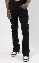 Jet black distressed denim jeans with a ripped and stacked fit.