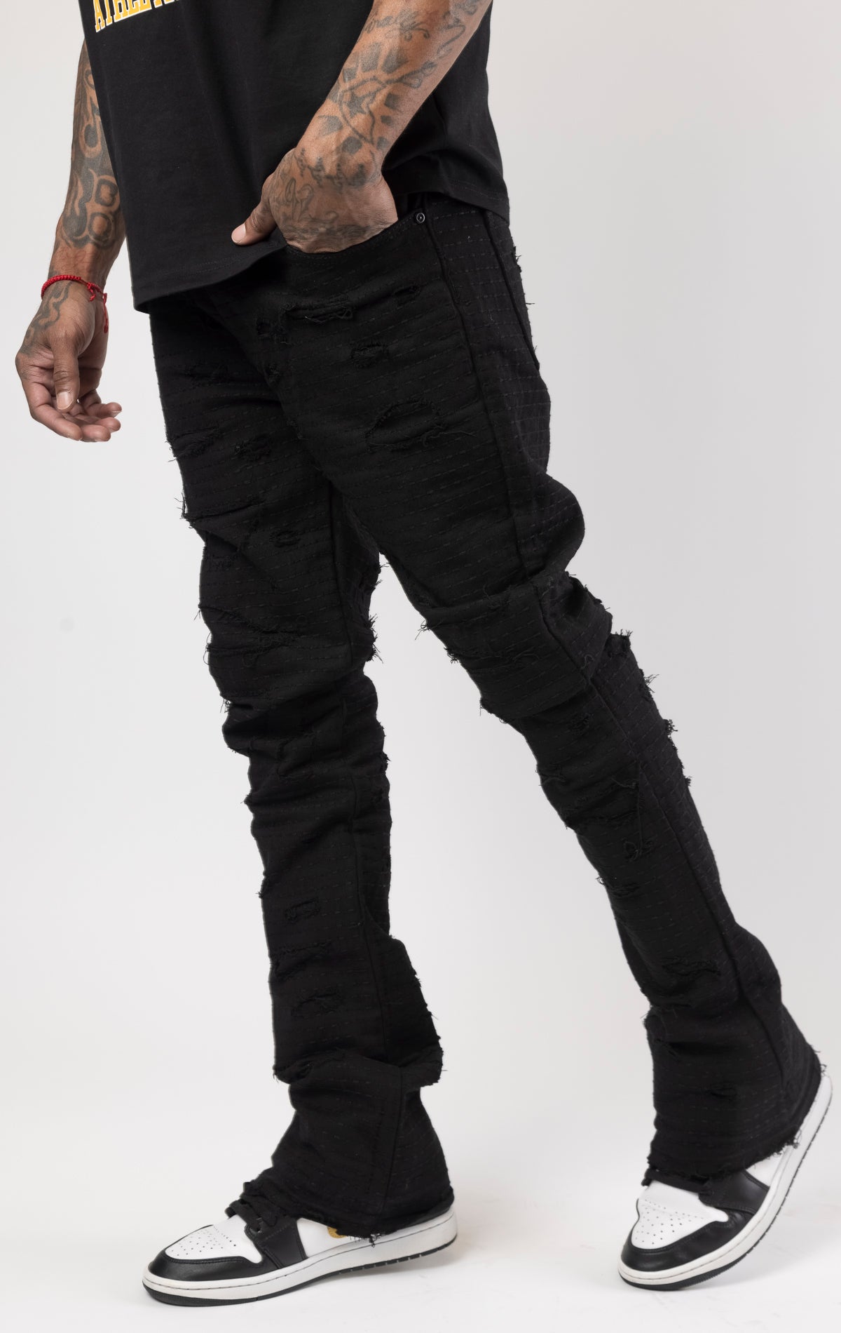 Jet black distressed denim jeans with a ripped and stacked fit.