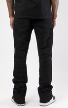 Jet black distressed denim jeans with a ripped and stacked fit.