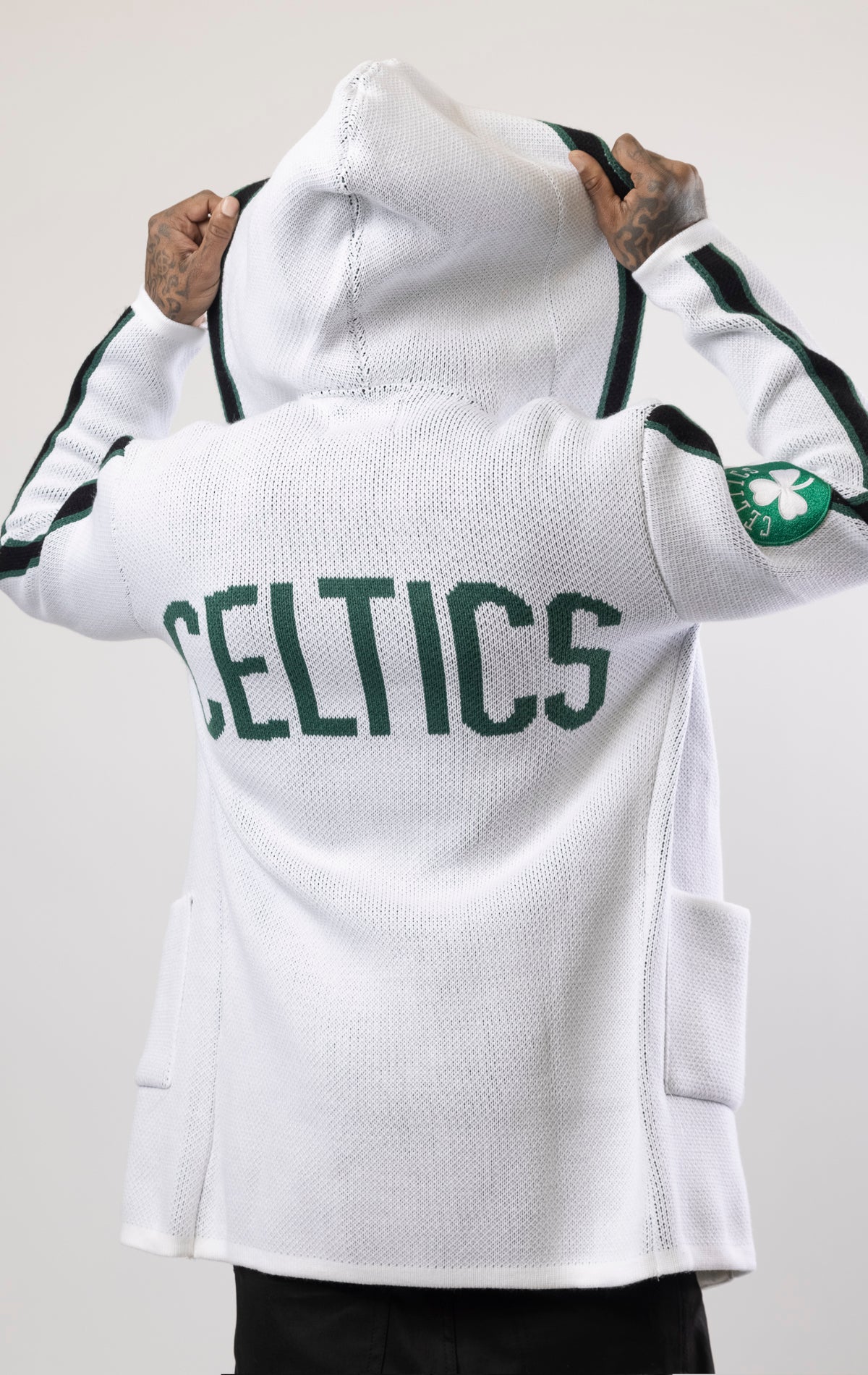 Upgrade your game day look with this Boston Celtics Cardigan Sweater. This cozy jacket is designed with a stylish three-quarter length and boasts bold team branding on the front, back, and sleeve. Complete with a full-zip closure, attached hood, and front pockets, this knit sweater offers both comfort and style.