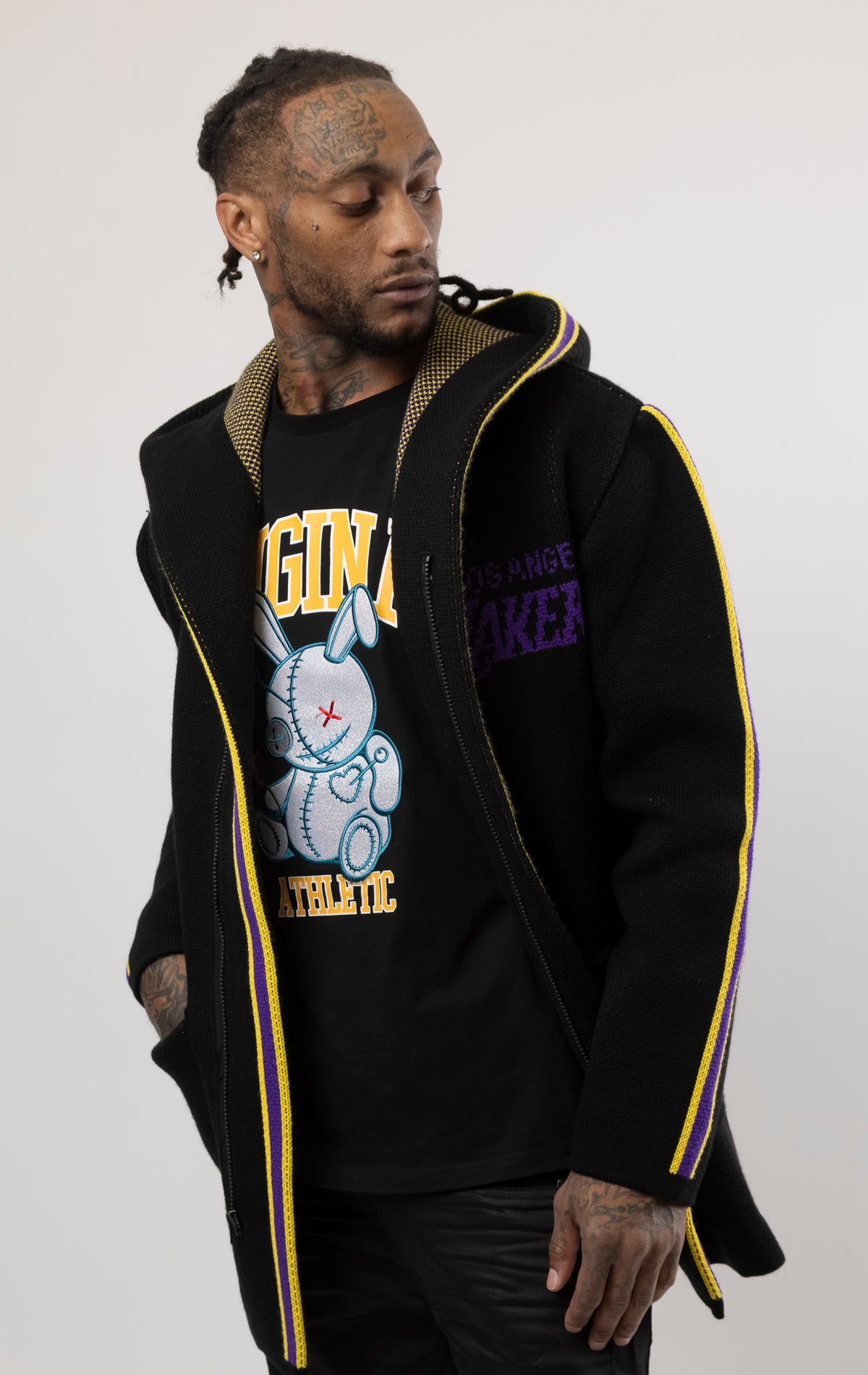 black LA LAKERS Cardigan Sweater. This cozy jacket is designed with a stylish three-quarter length and boasts bold team branding on the front, back, and sleeve. Complete with a full-zip closure, attached hood, and front pockets, this knit sweater offers both comfort and style.