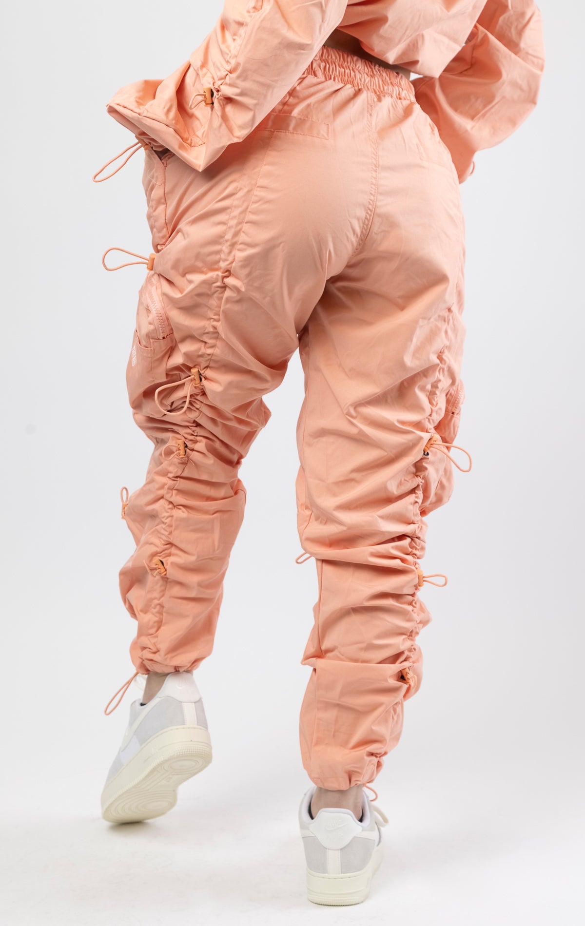 Sand coral multi-bungee jogger featuring a Brook fit, snap buttons, an adjustable waist and wide pockets.