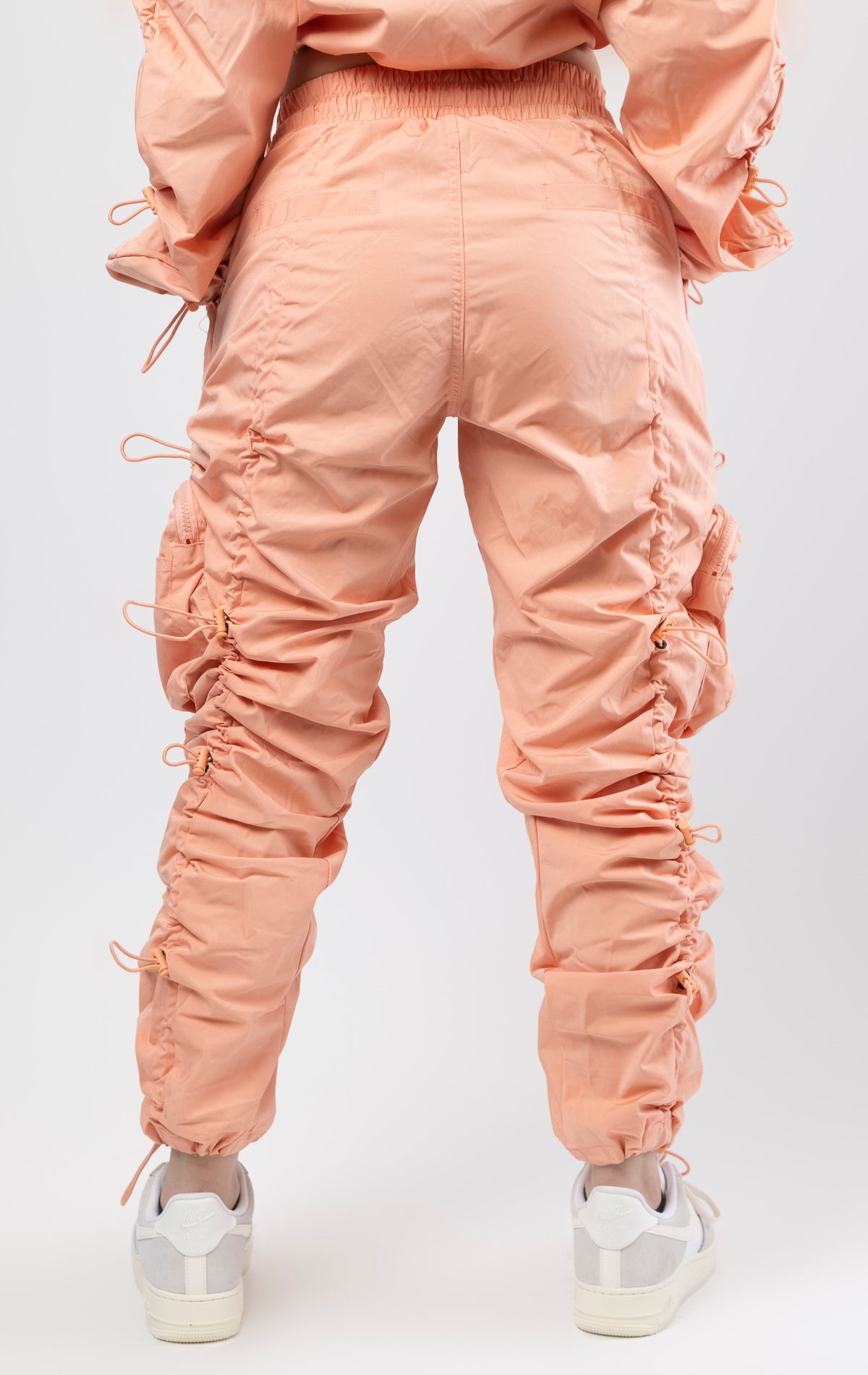 Sand coral multi-bungee jogger featuring a Brook fit, snap buttons, an adjustable waist and wide pockets.